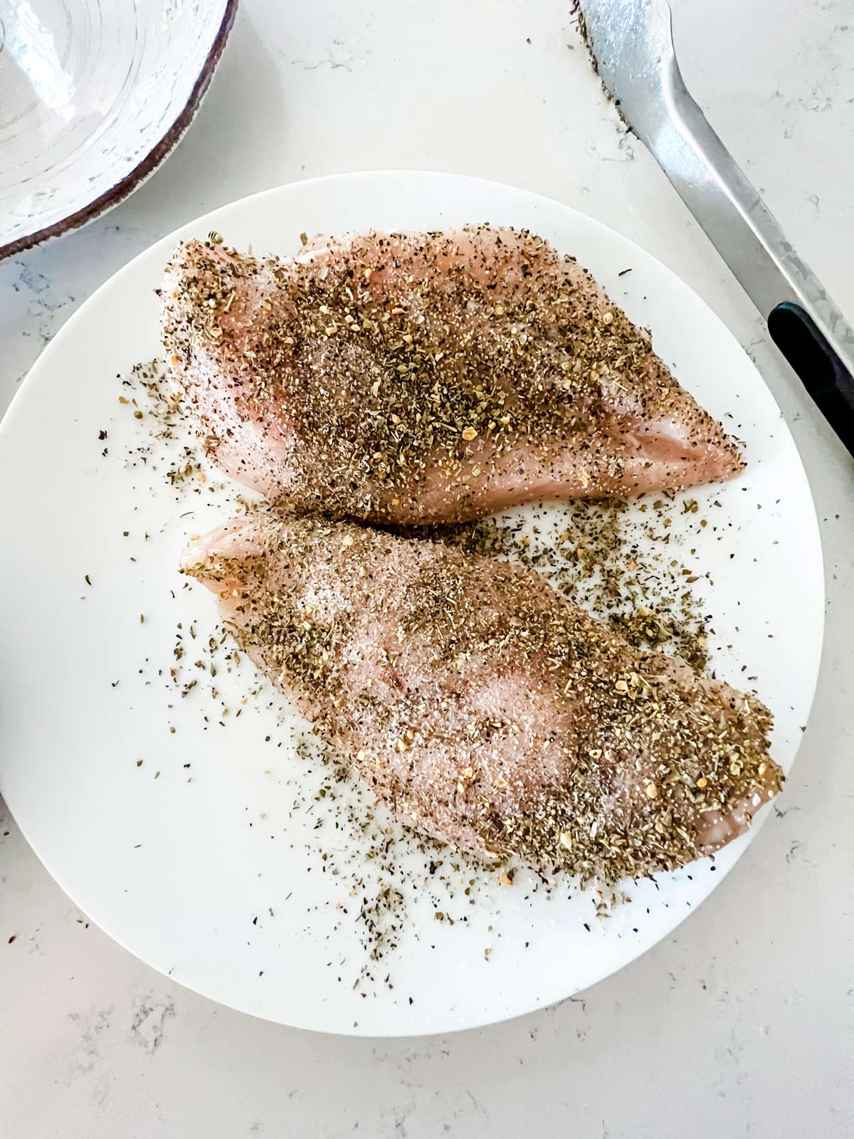 Raw seasoned chicken on a plate.