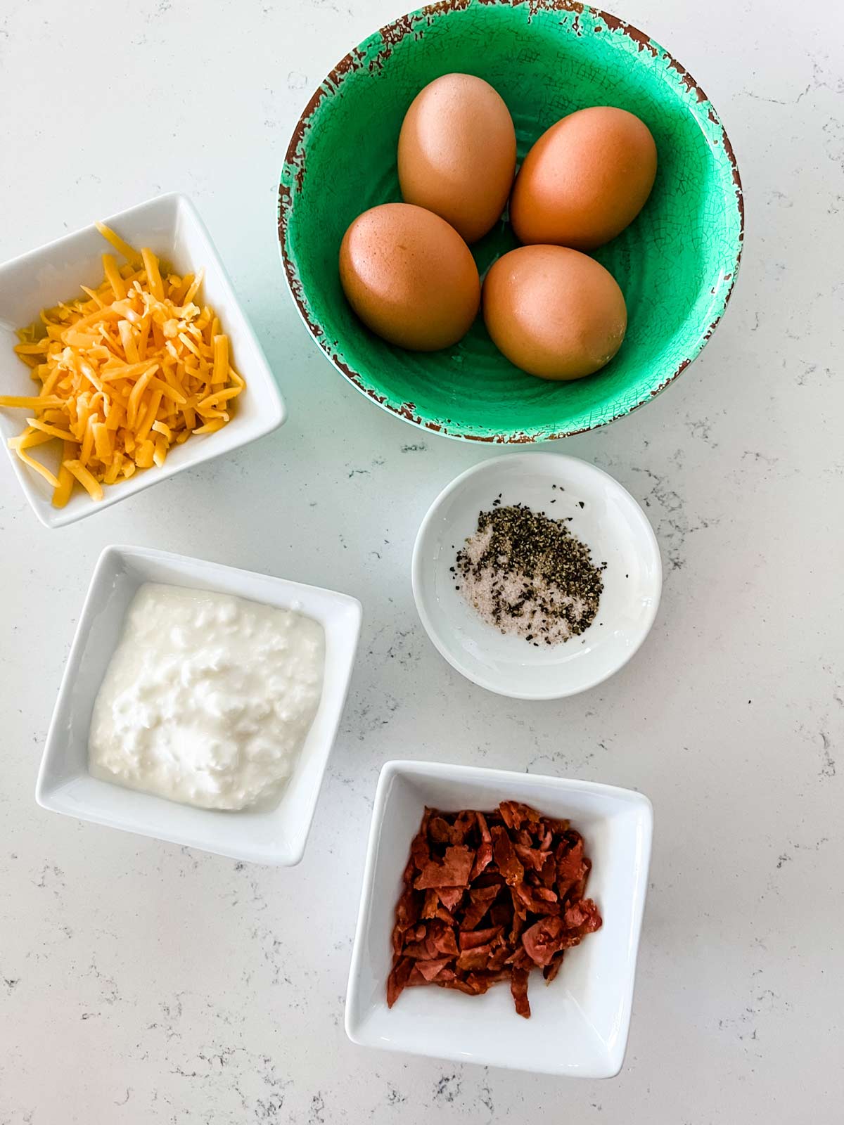 Ingredient photo of eggs, cheese, cottage cheese, bacon, and seasonings.