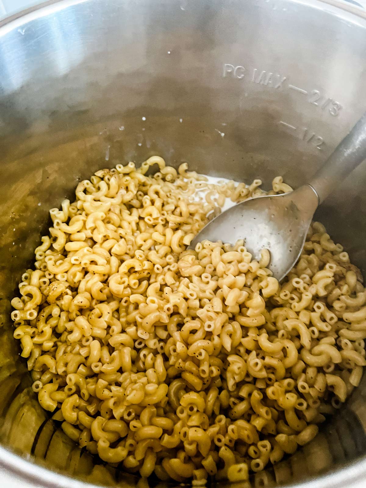 Milk stirred into cooked elbow noodles in an Instant Pot.