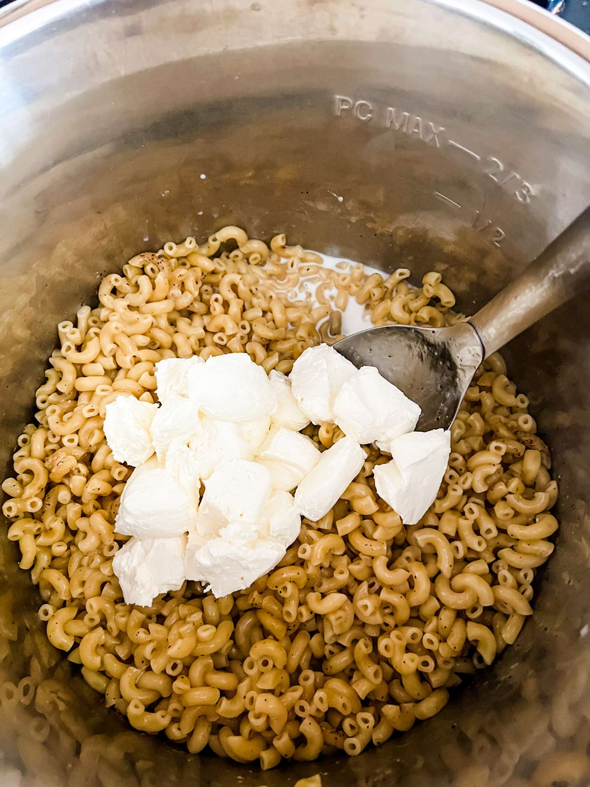 Cream cheese added to the top of cooked noodles and milk in an Instant Pot.