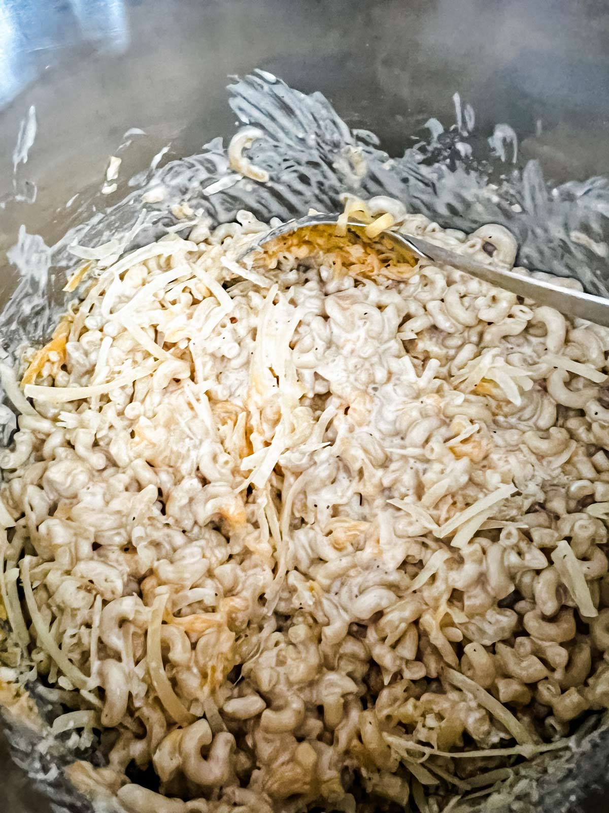 Cheese being stirred into elbow noodles, milk, and cream cheese.