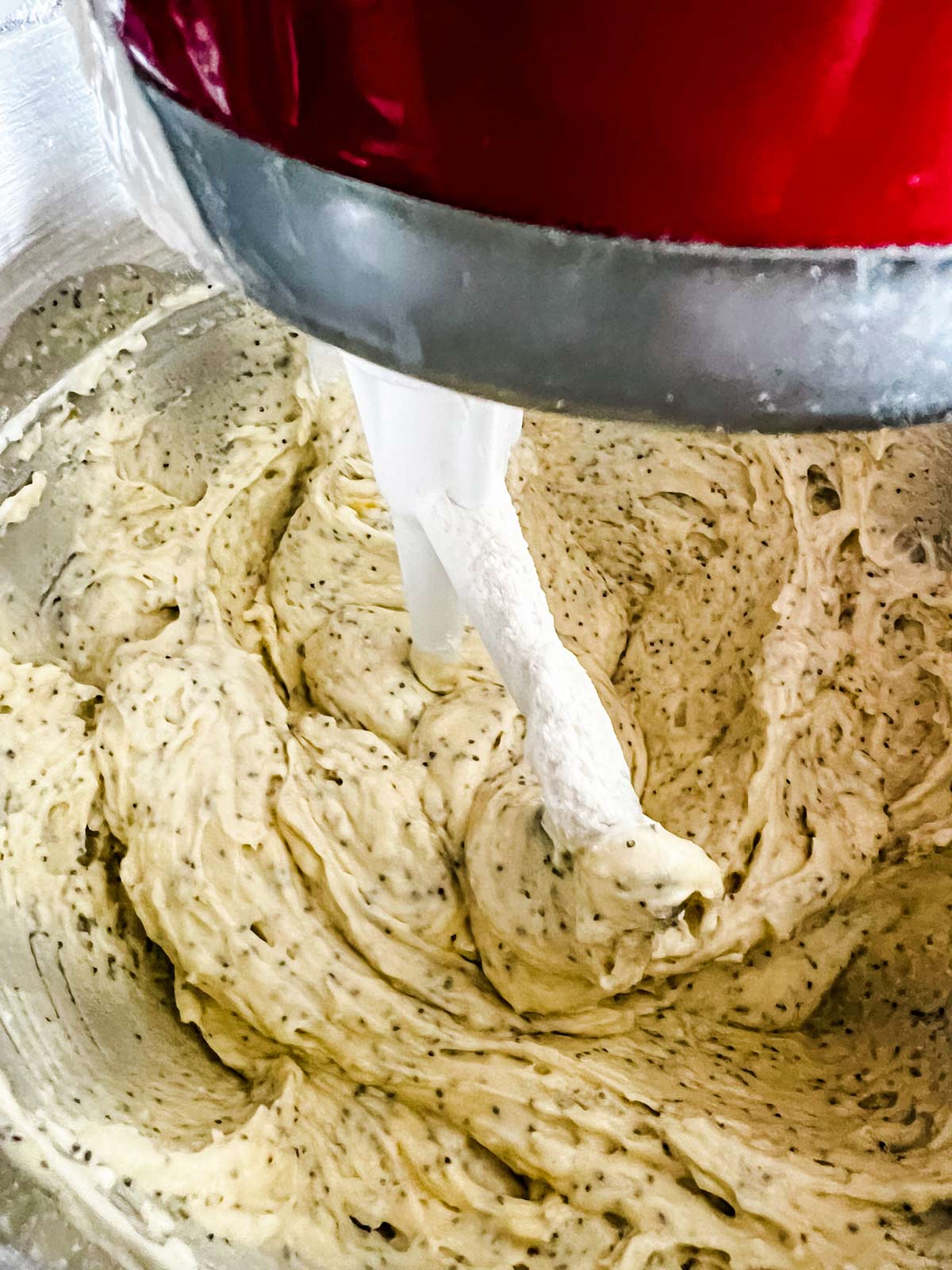 Lemon loaf batter being finished up in a  red KitchenAid stand mixer.