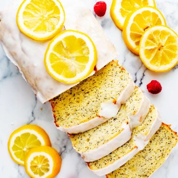 Overhead square photo of a lemon loaf on a white marble board garnished with candied lemons.