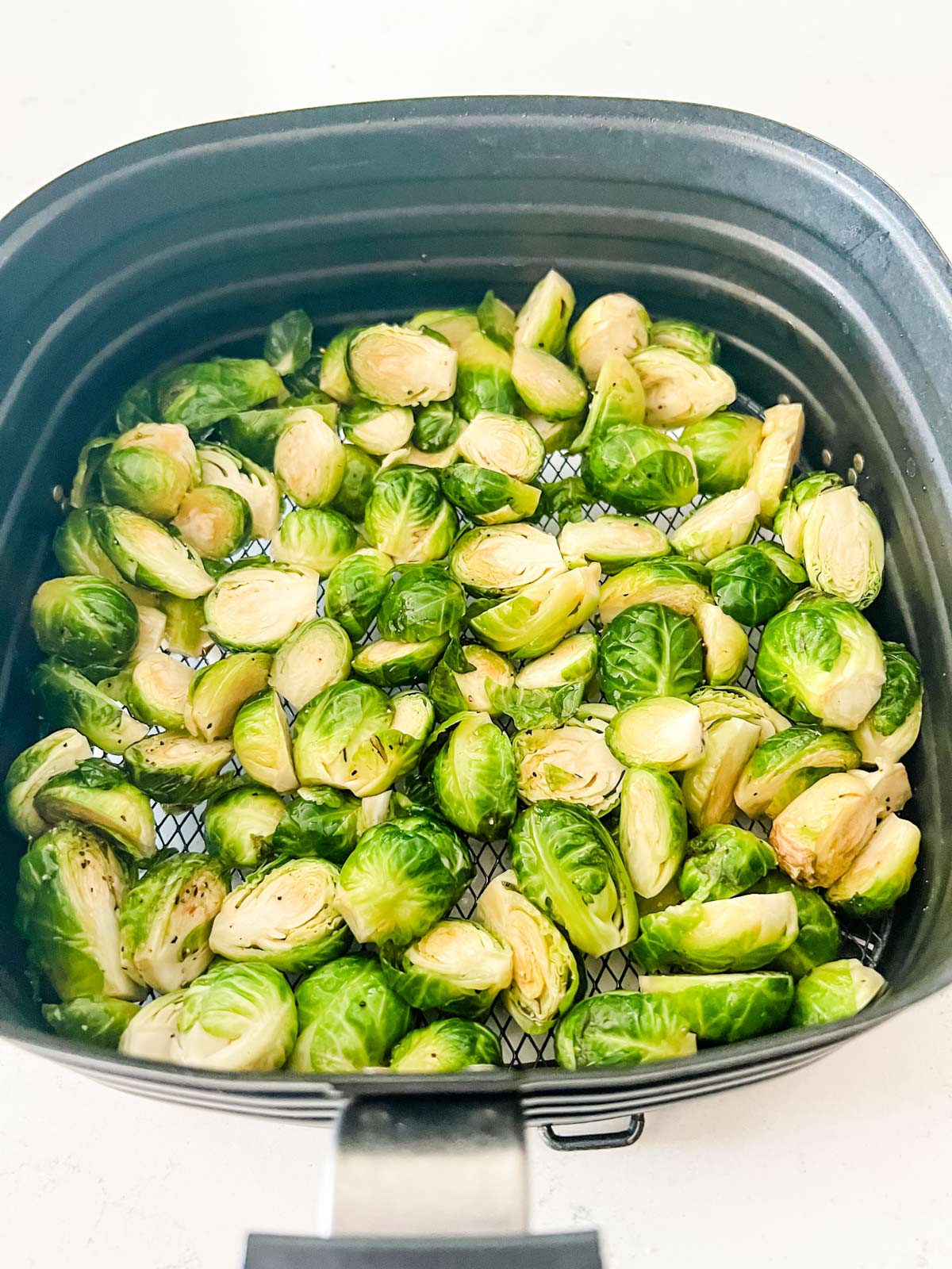 Brussels sprouts in an air fryer basket ready to cook.