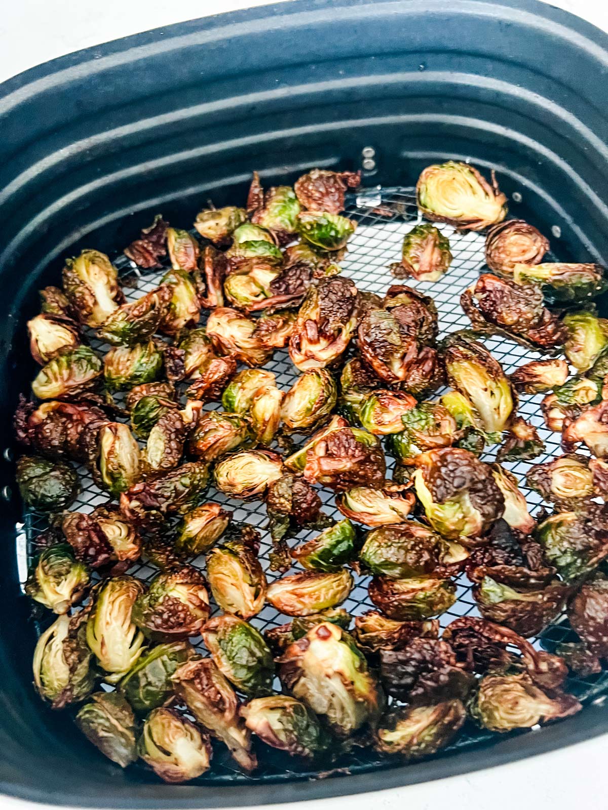 Crispy brussels sprouts in an air fryer basket.