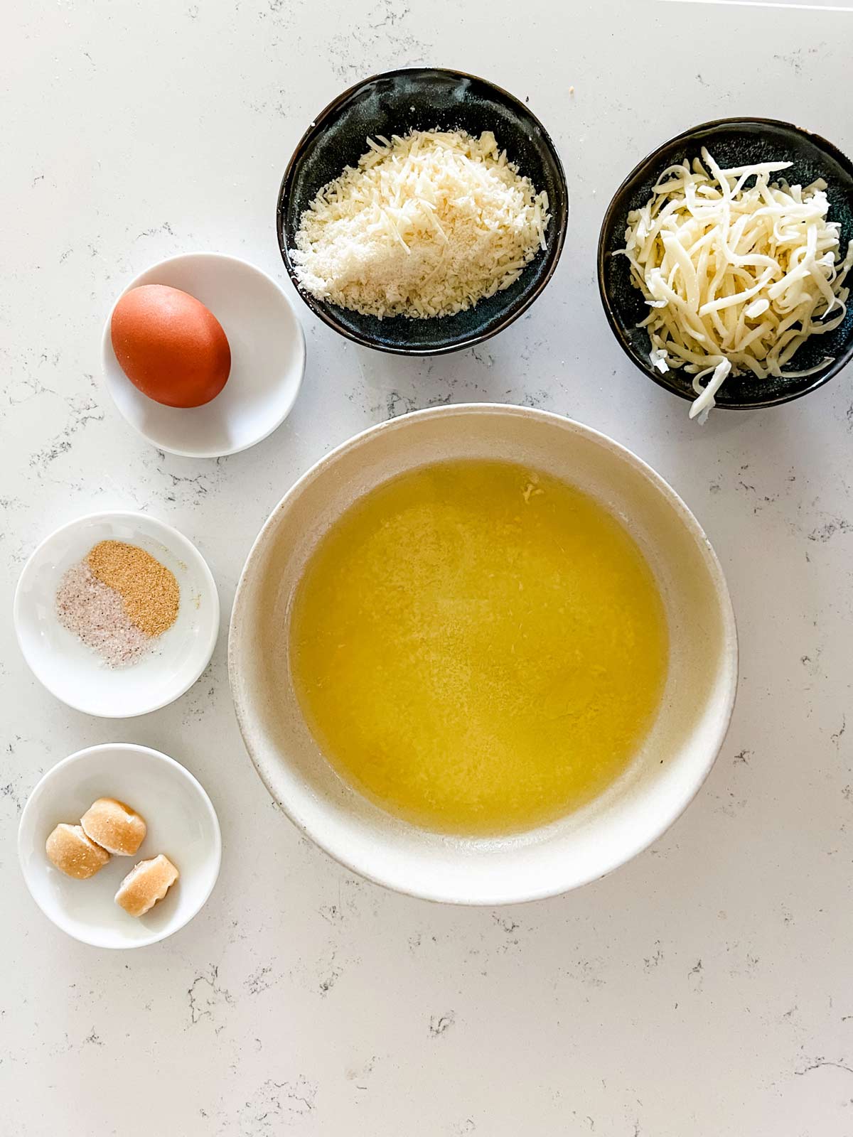 Garlic, oil, parmesan, mozzarella, egg, and seasonings in prep containers.