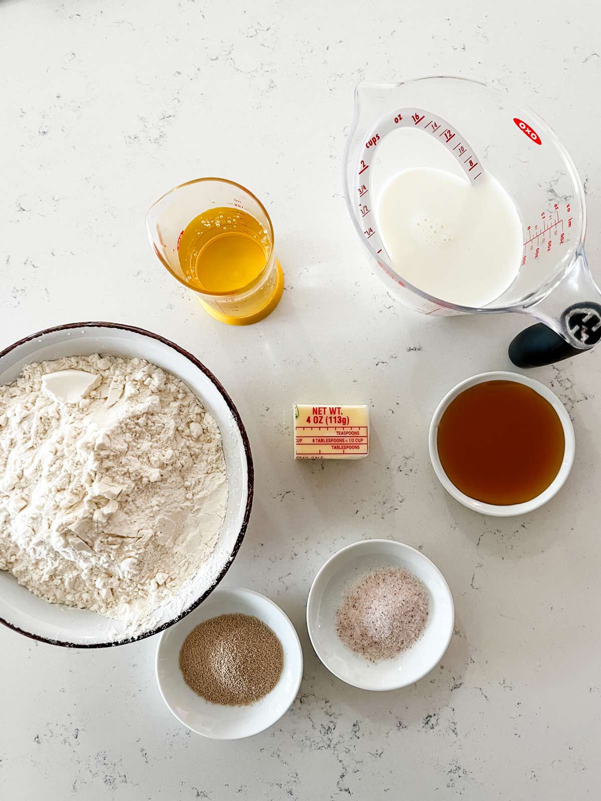 Overhead photo of milk, water, butter, honey, bread flour, yeast, and salt.