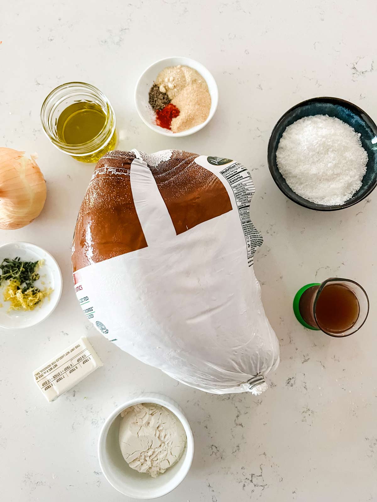Overhead photo of a turkey breast, salt, butter, flour, oil, onion, and seasonings.