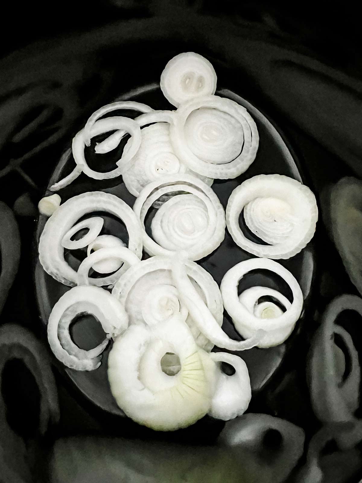 Onions in the bottom of a slow cooker.