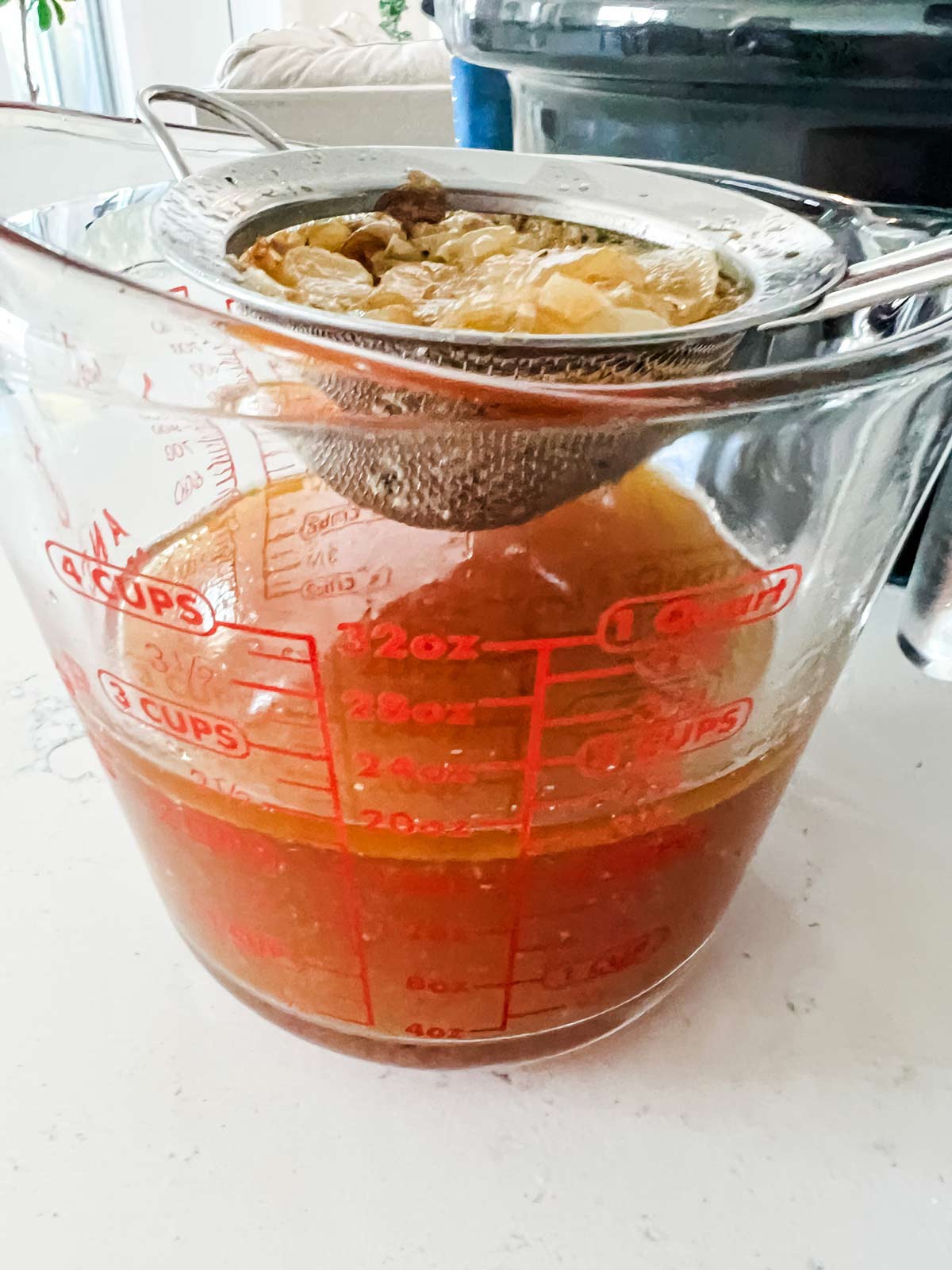 Straining liquids into a large measuring cup from Crockpot Turkey Breast.