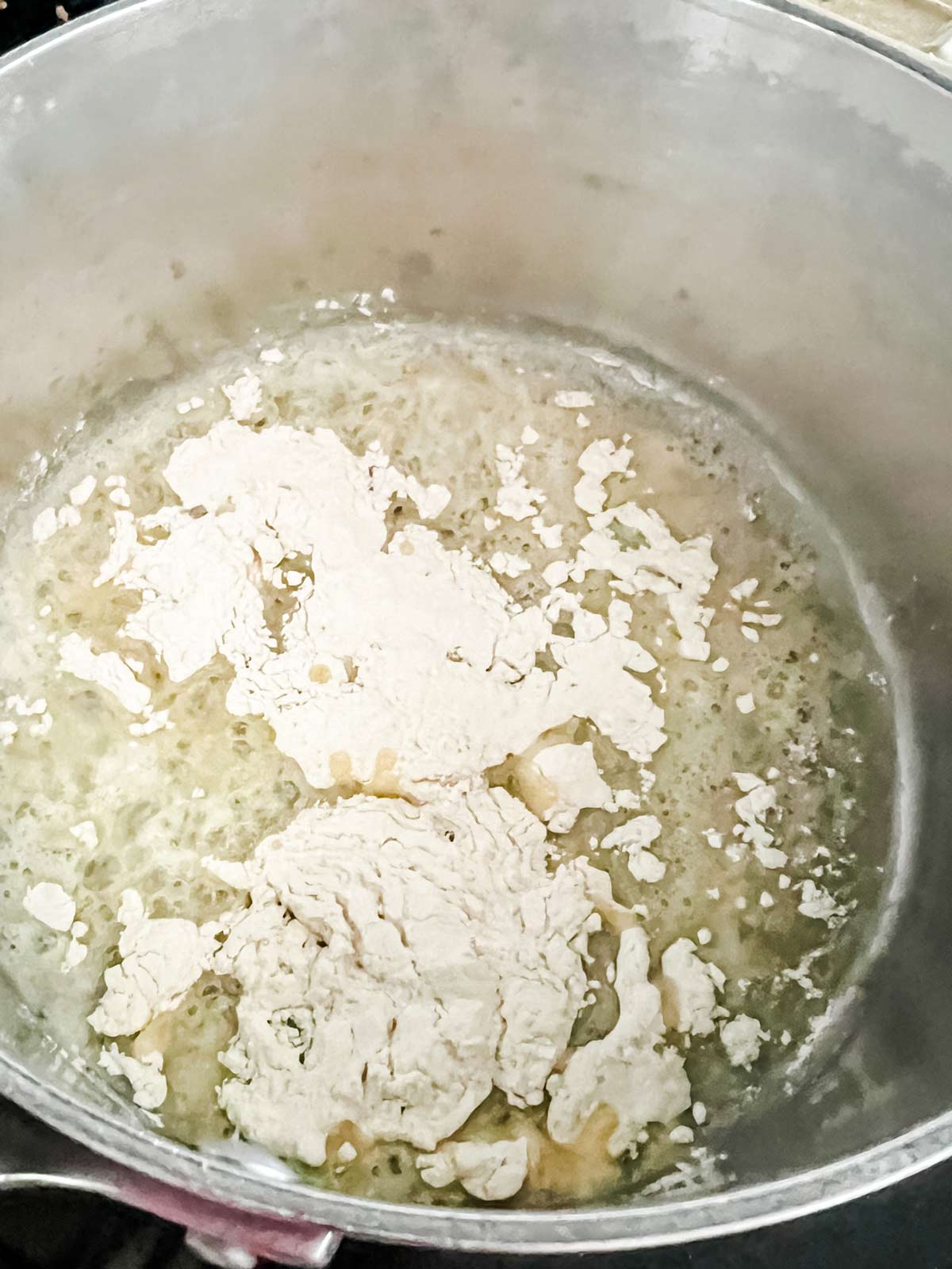 Melted butter in a saucepan with flour sprinkled on top of it.