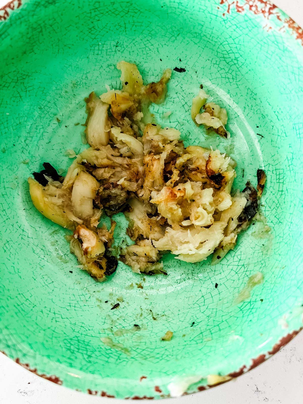 Mashed garlic in a small green bowl.