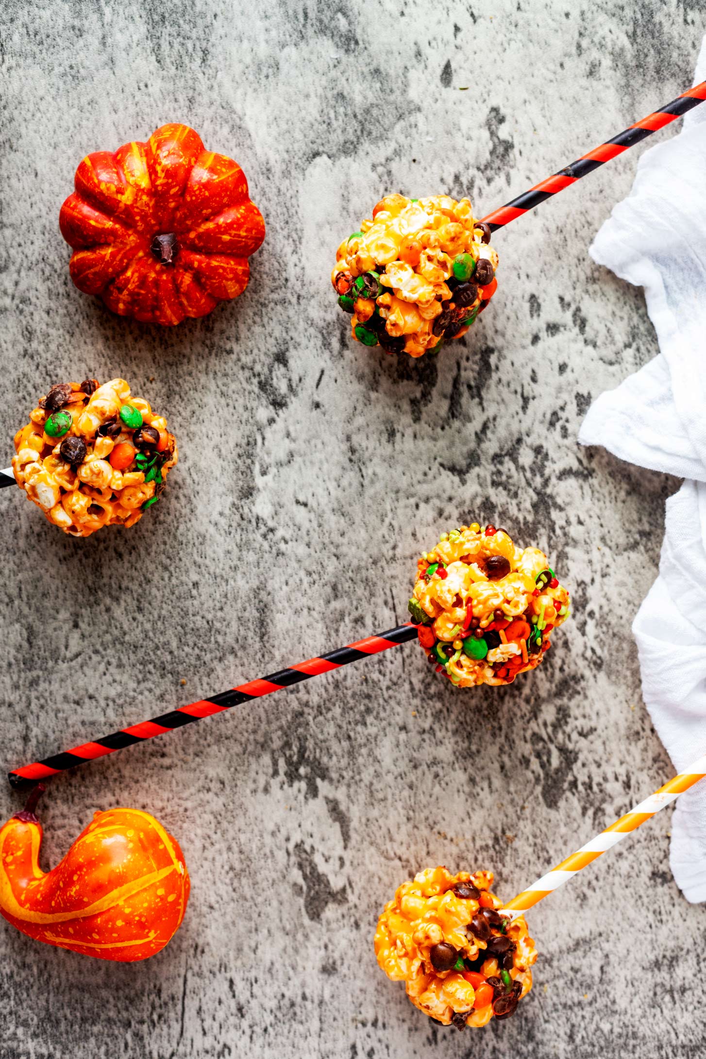 Overhead photo of halloween popcorn balls sitting next to small pumpkins.