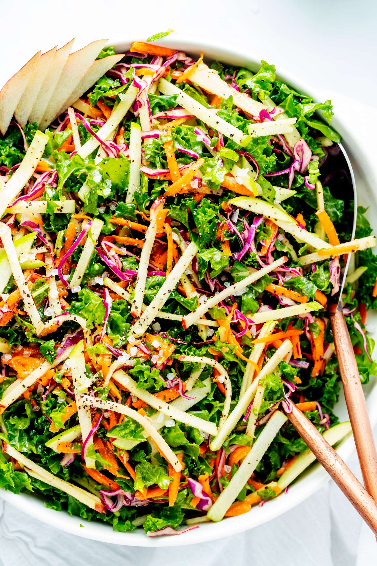 Close up photo of a kale apple slaw with serving spoons.