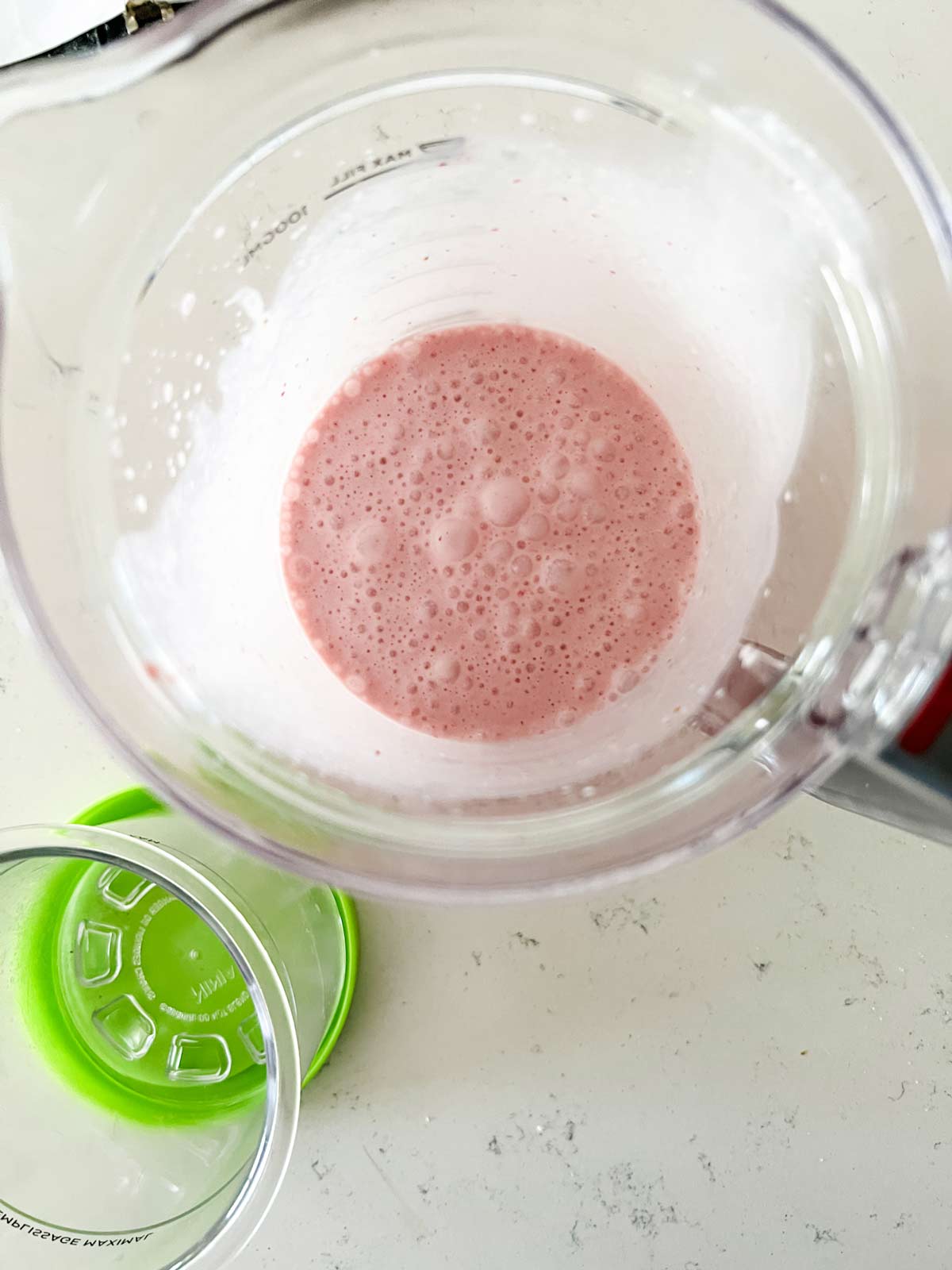 The blended base for strawberry ice cream in a blender.