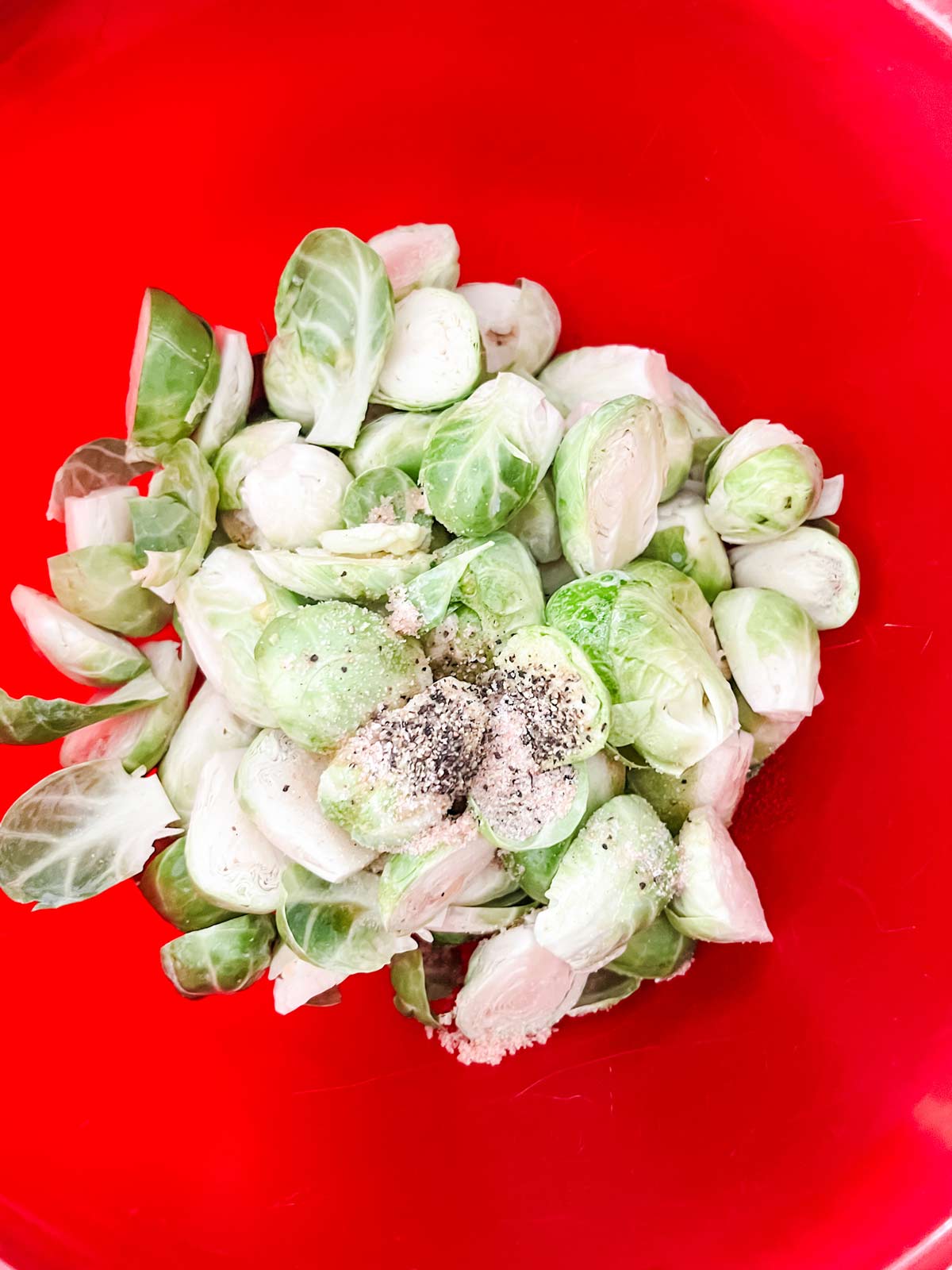 Brussels sprouts and seasonings in a red bowl.