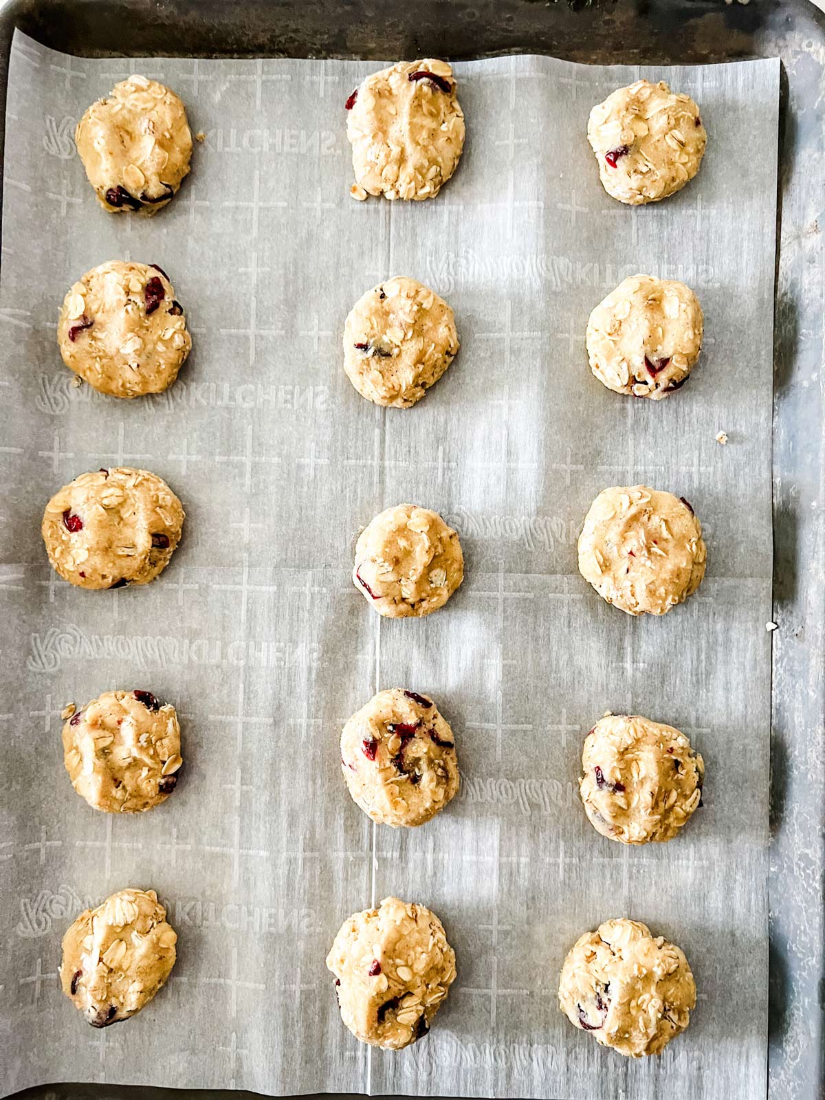 Oatmeal Craisin Cookies rolled and then pressed down on a parchment lined cookie sheet.