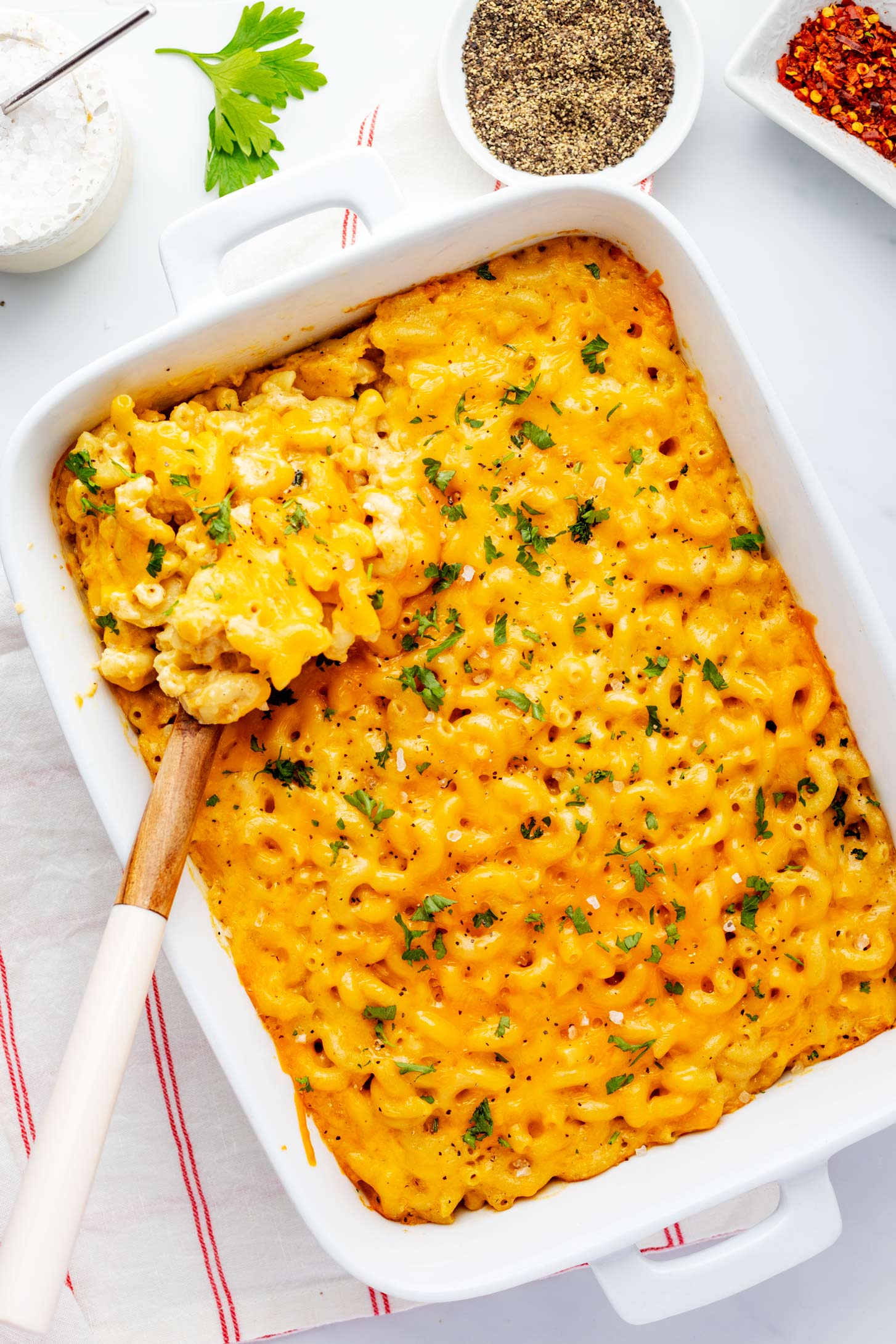 Overhead photo of a casserole dish with old fashioned baked macaroni and cheese with a spoonful being scooped.