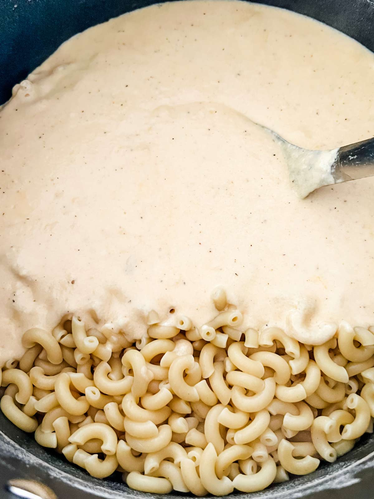 Elbow noodles being added to a cheese sauce.