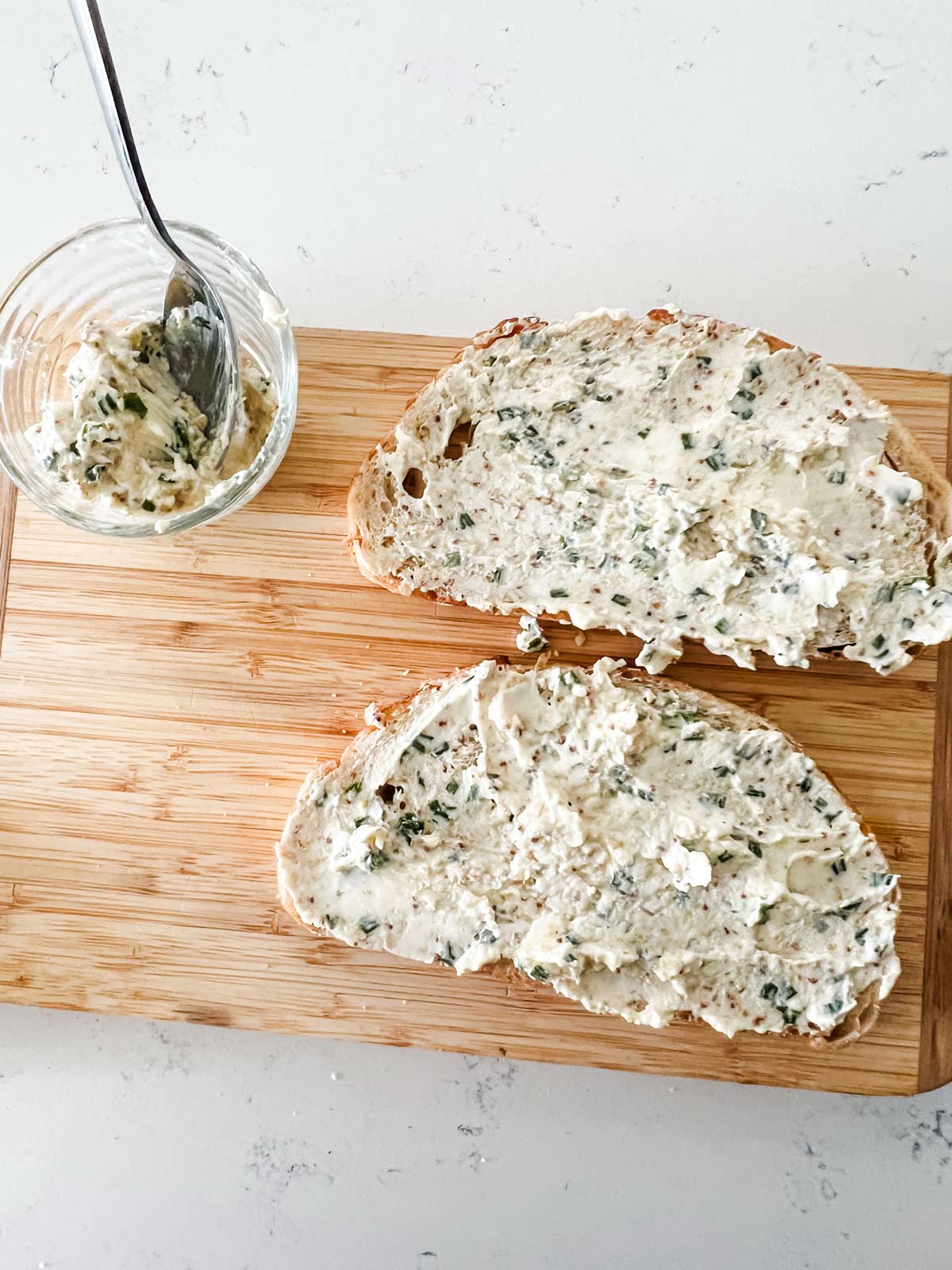 Two pieces of bread with a cream cheese chive spread.