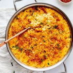 Overhead square photo of gouda mac and cheese in a large skillet with a serving spoon.