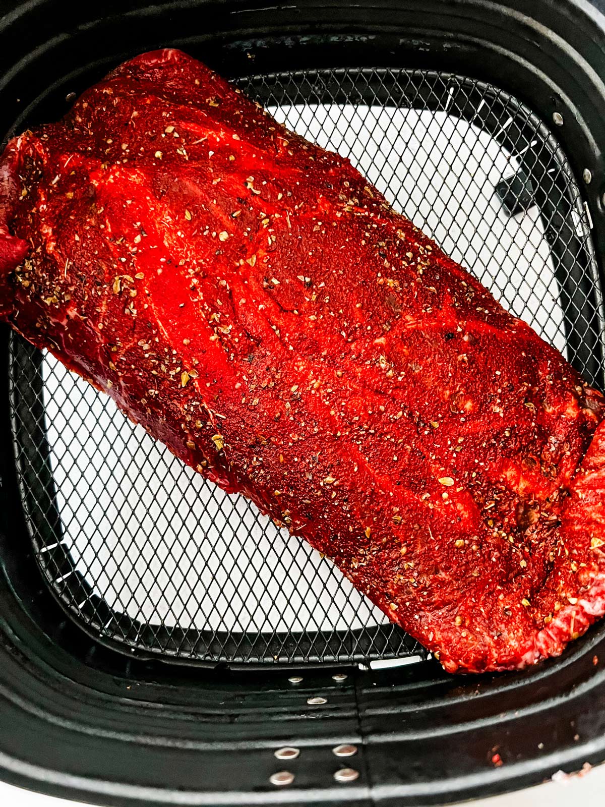 Flat iron steak in an air fryer basket ready to cook.
