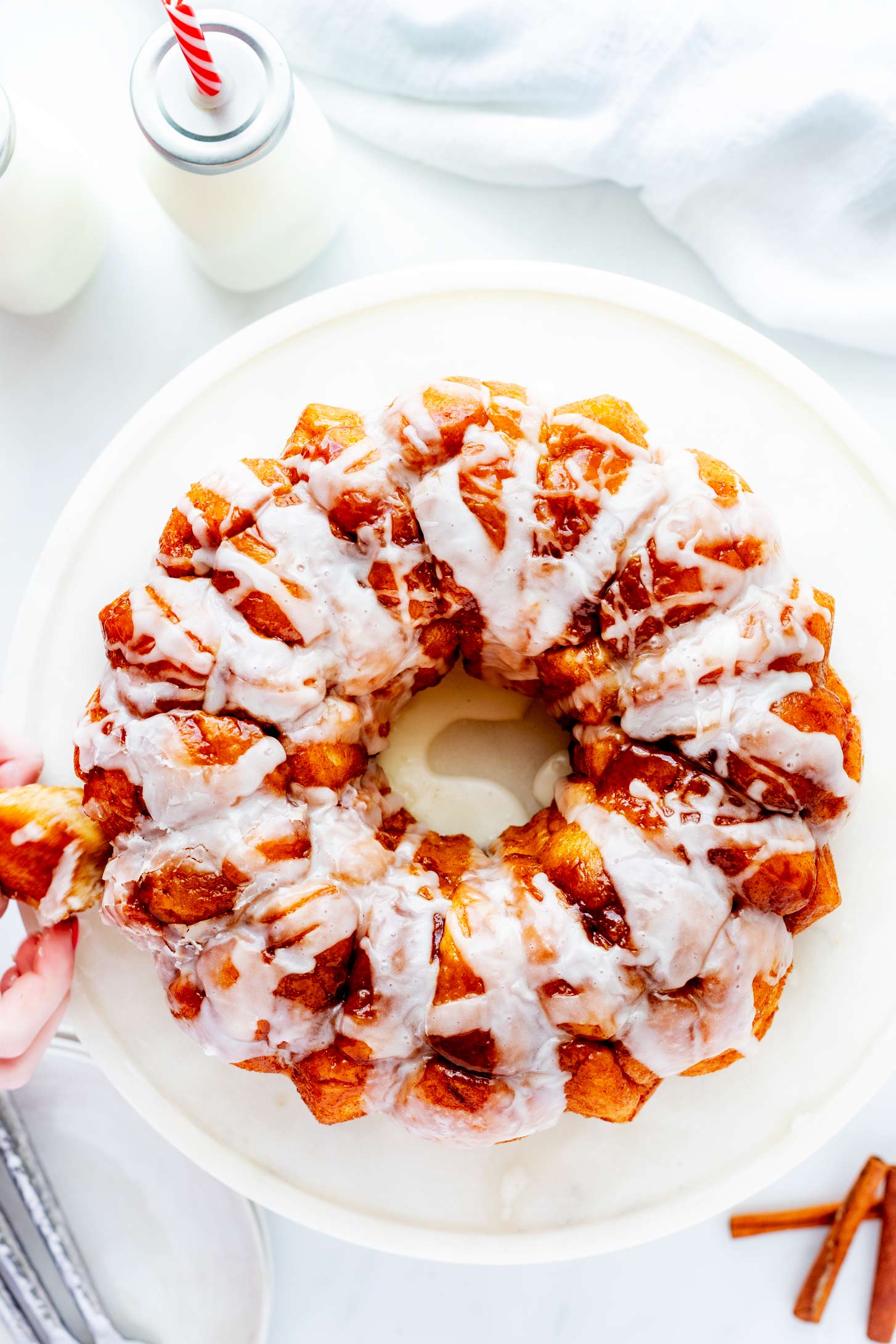 Overhead photo of bread machine monkey bread on a cake stand with a piece being pulled from it.