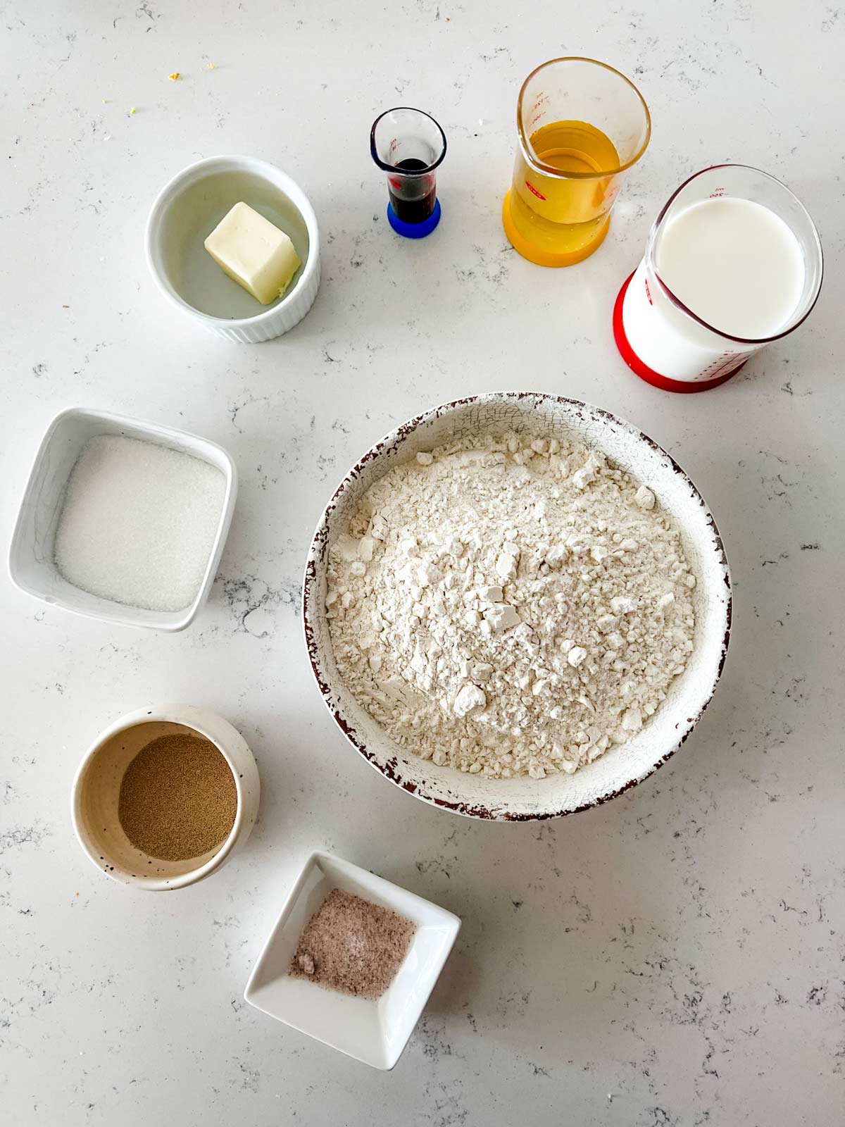 Overhead photo of flour, milk, water, vanilla, butter, sugar, yeast, and salt.