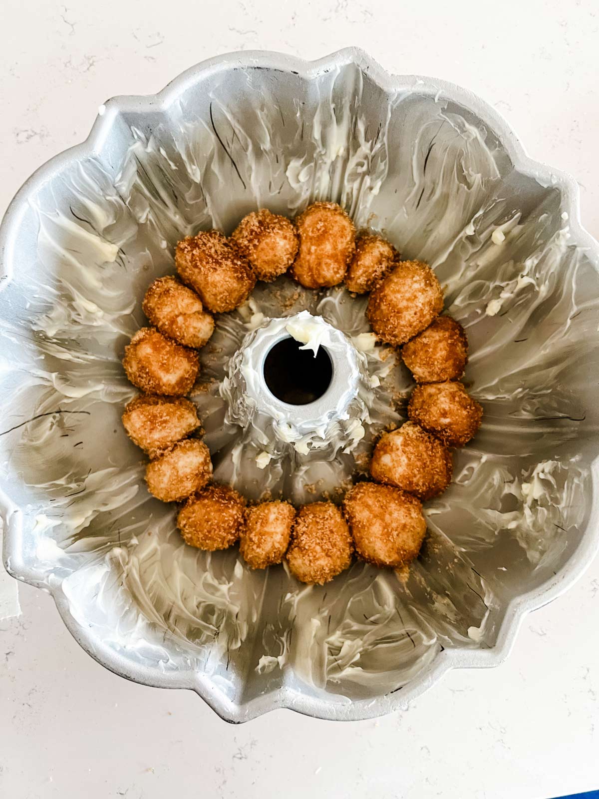 Balls for monkey bread added to a greased Bundt pan.