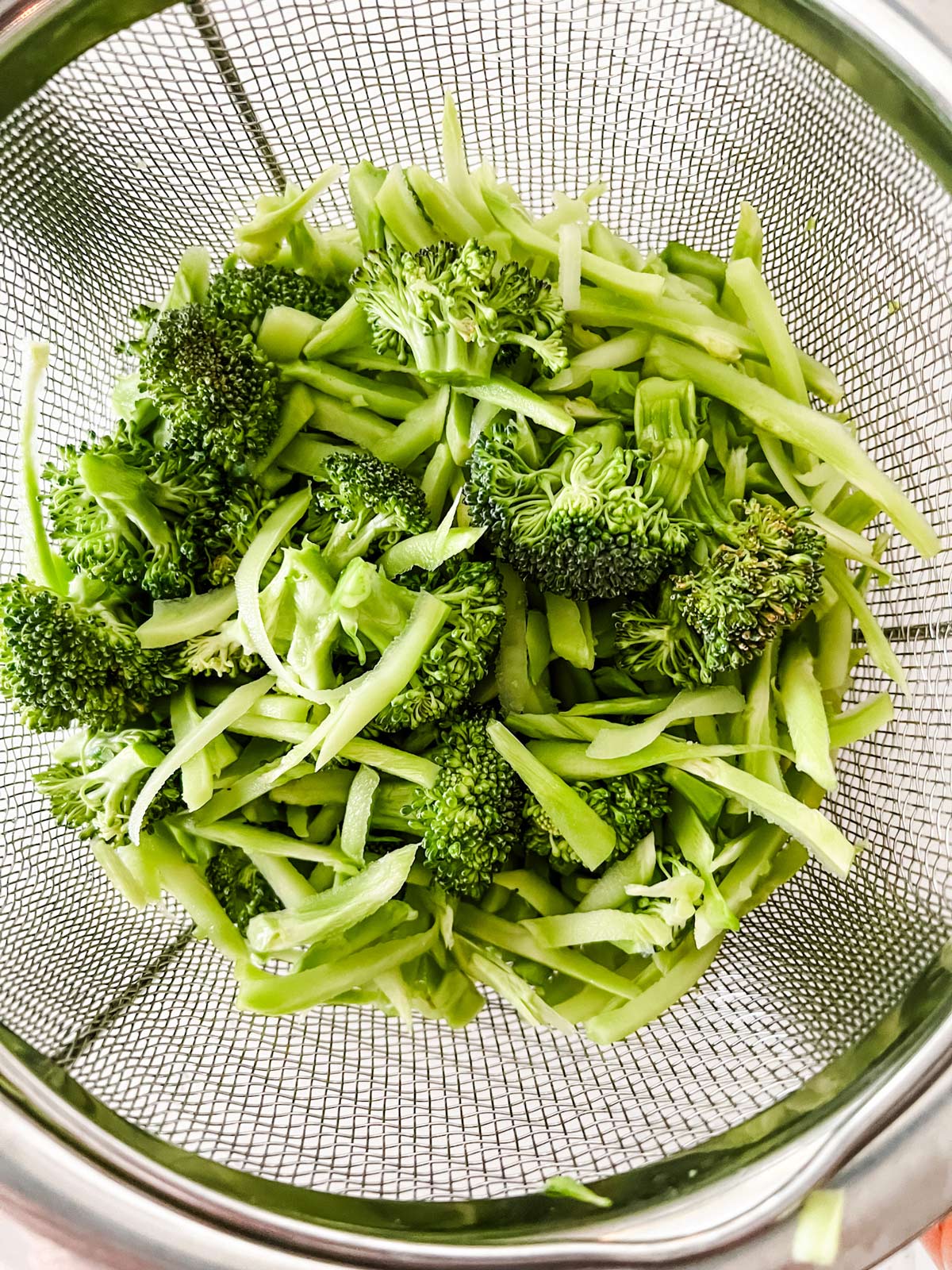 Photo of broccoli and shredded broccoli stems in a steamer basket.