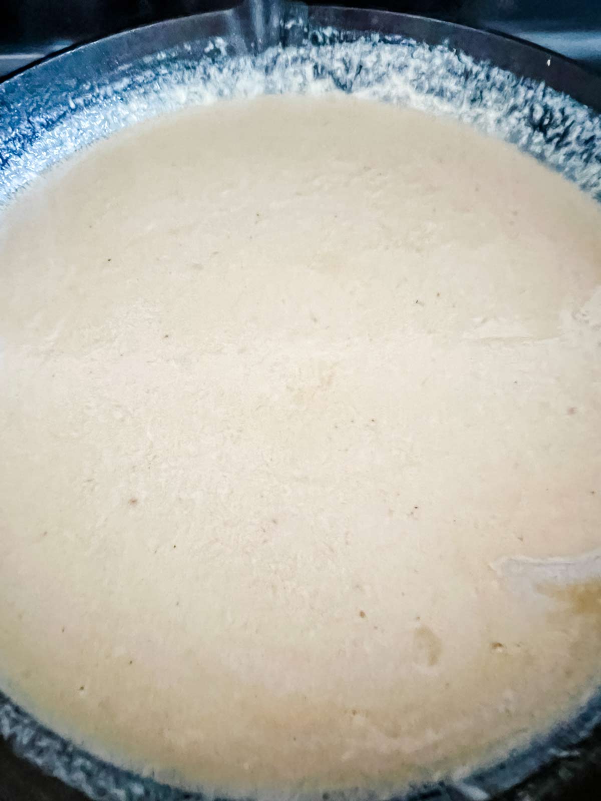 A cheesy white cream sauce in a cast iron skillet.