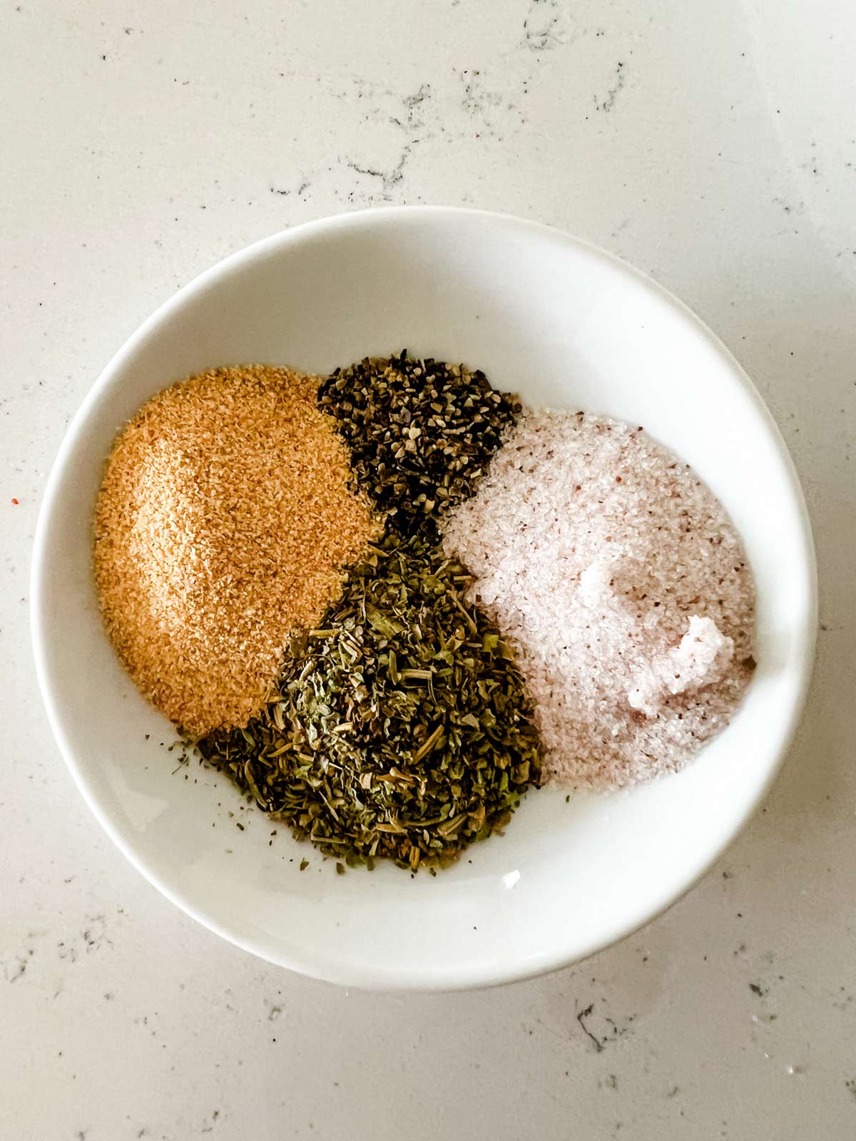 Overhead photo of seasoning mixtures in a small white bowl.