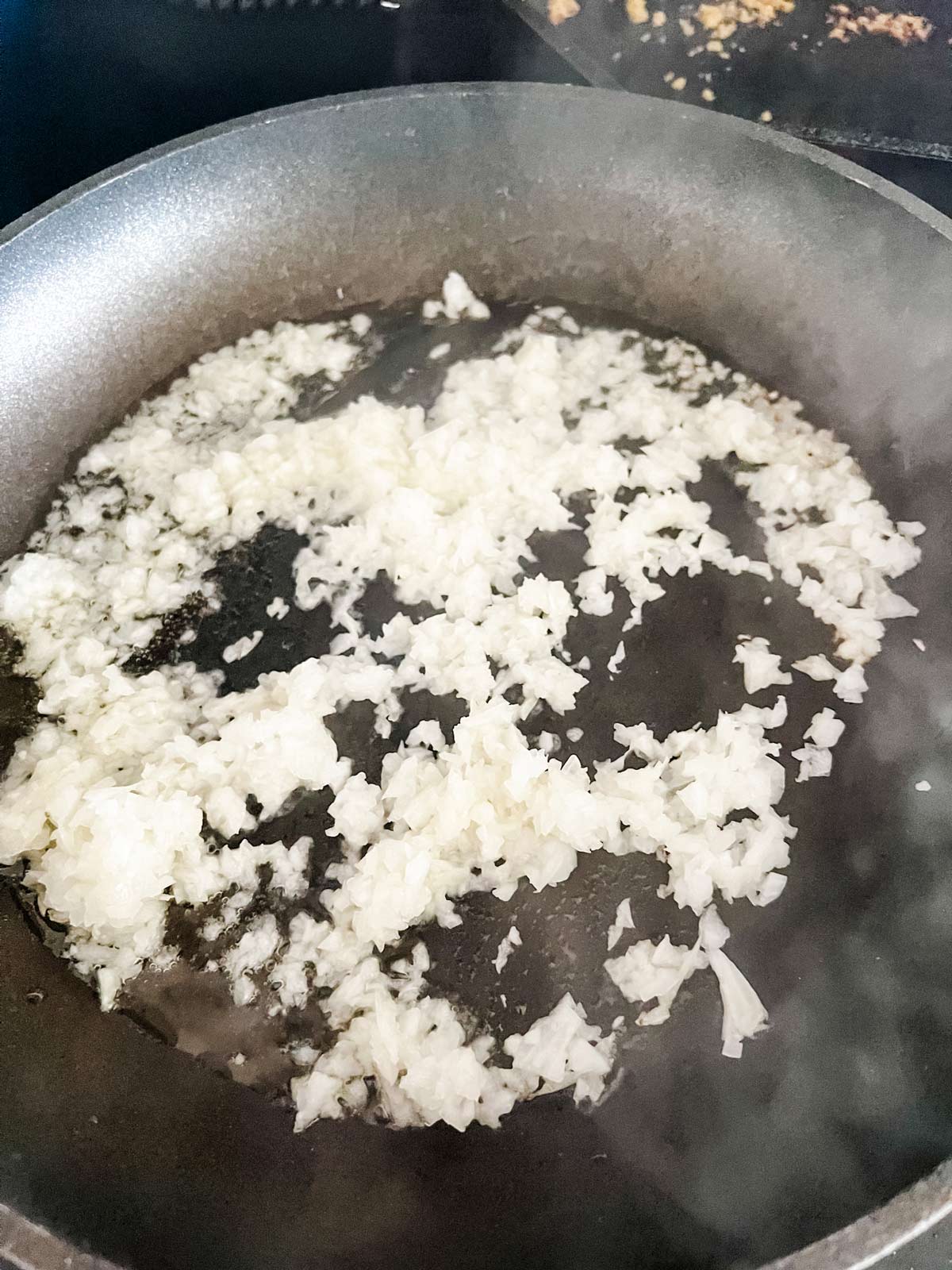 Photo of finely chopped onion cooking in a skillet.