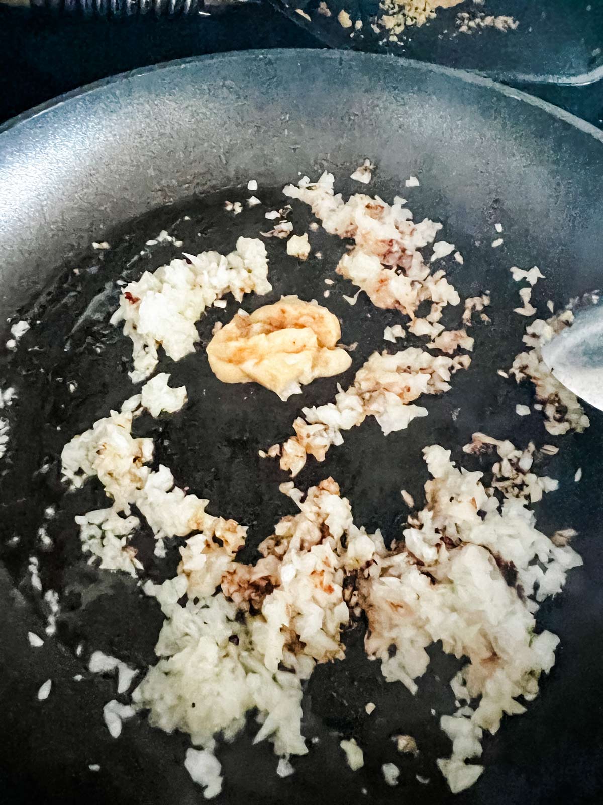 Photo of onion and garlic cooking in a skillet.