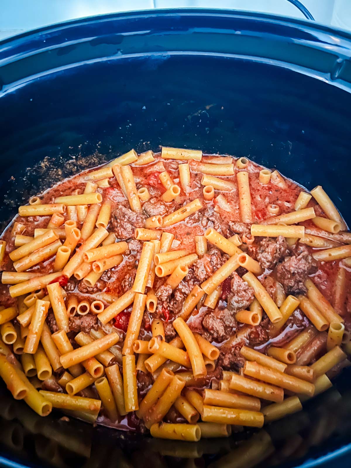 Baked ziti in a slow cooker before the cheese has been added.