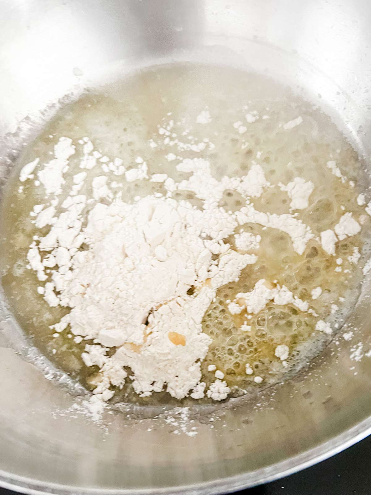 Flour sprinkled on top of melted butter in a large pot.
