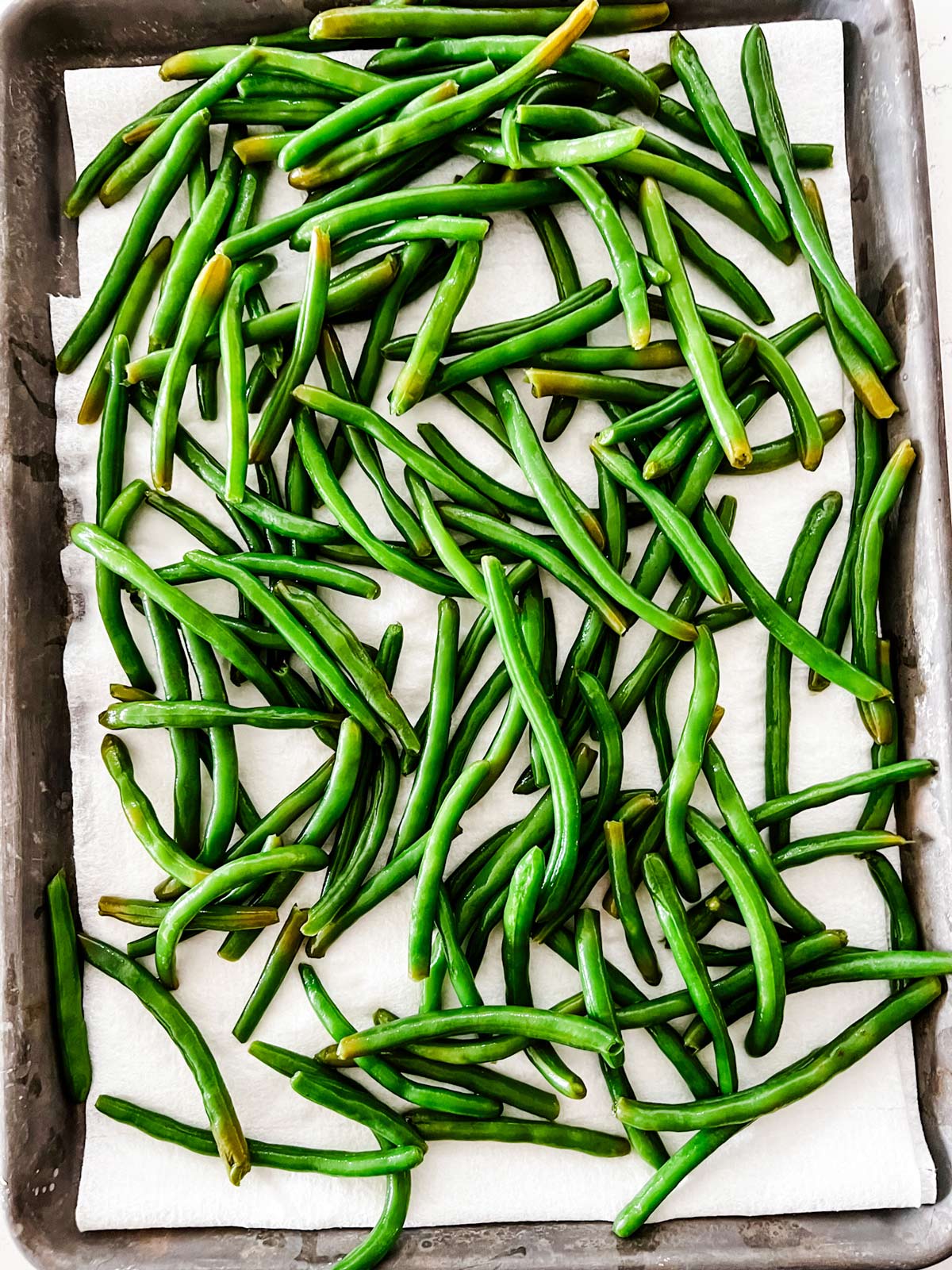 Green beans on a paper towel lined baking sheet.
