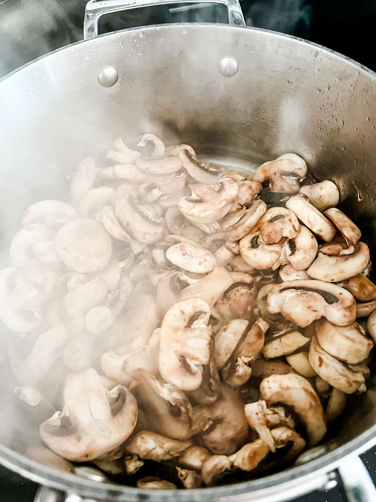 Mushrooms cooking in a large pot.