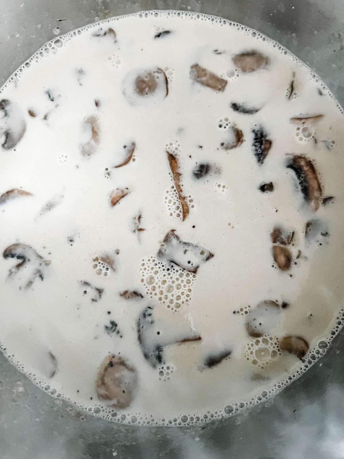 A cream sauce with mushrooms in a large pot.