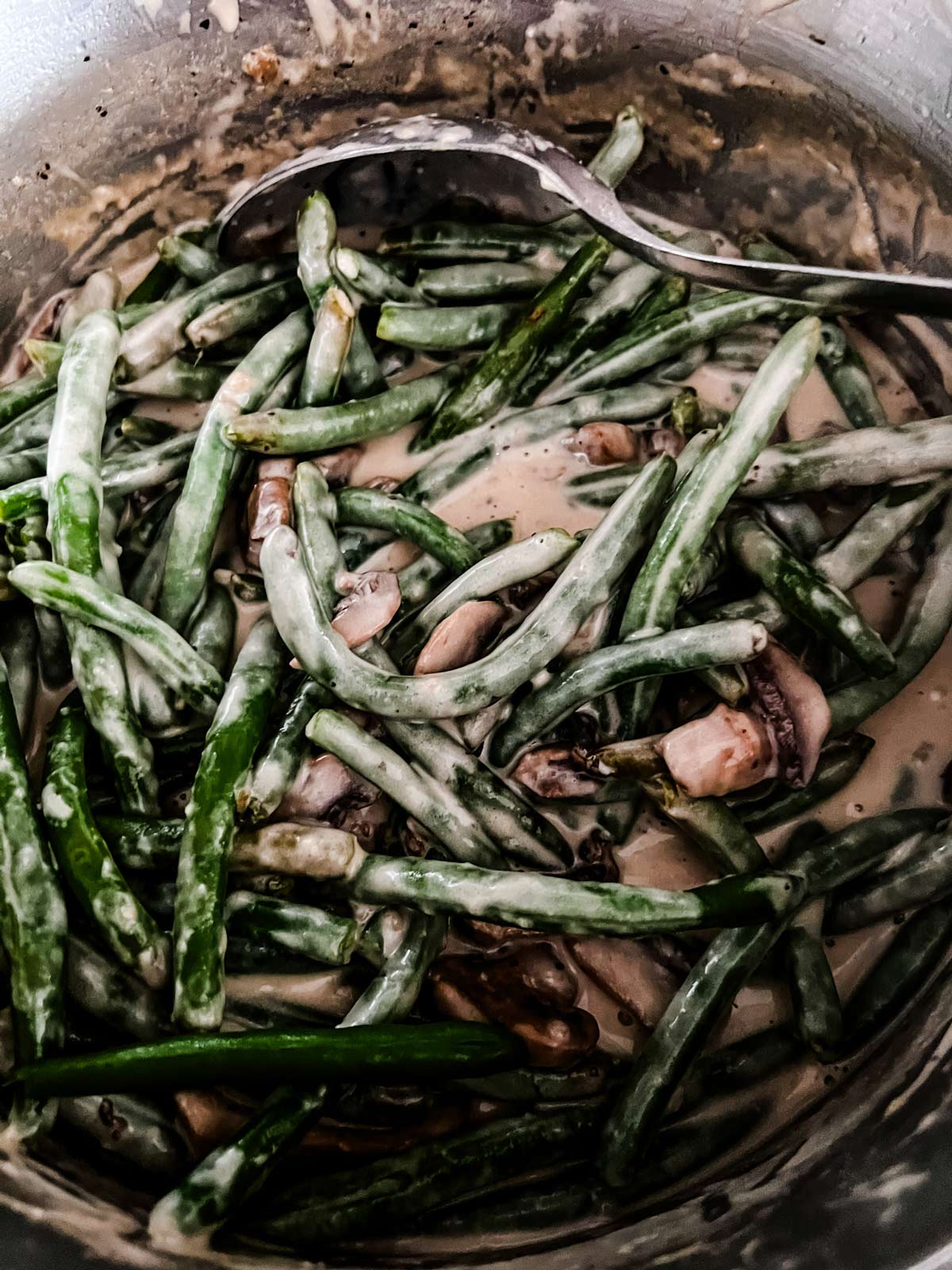 Green beans and mushrooms in a cream sauce in a large pot.