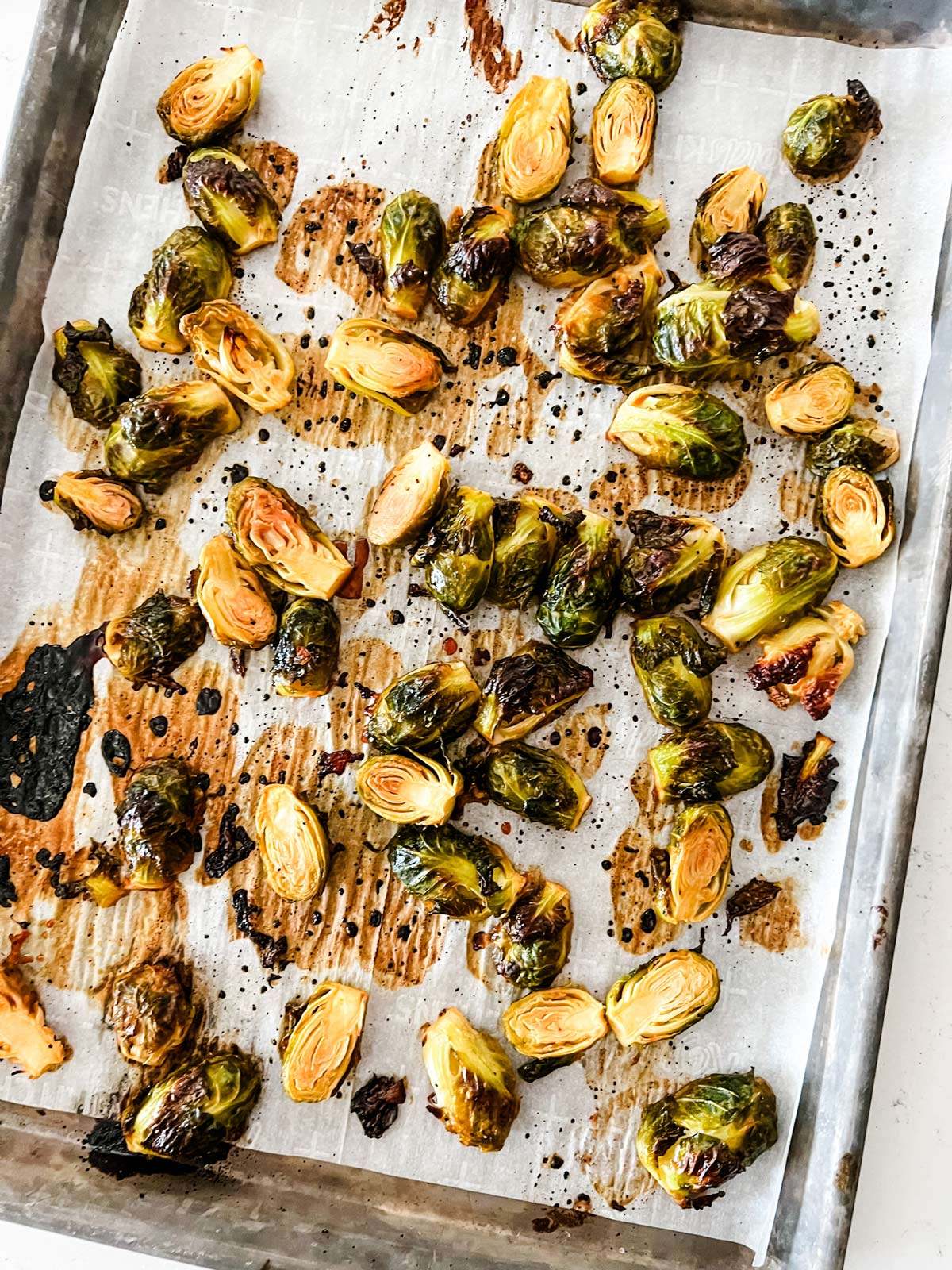 Overhead photo of roasted brussels sprouts on a parchment lined baking sheet.