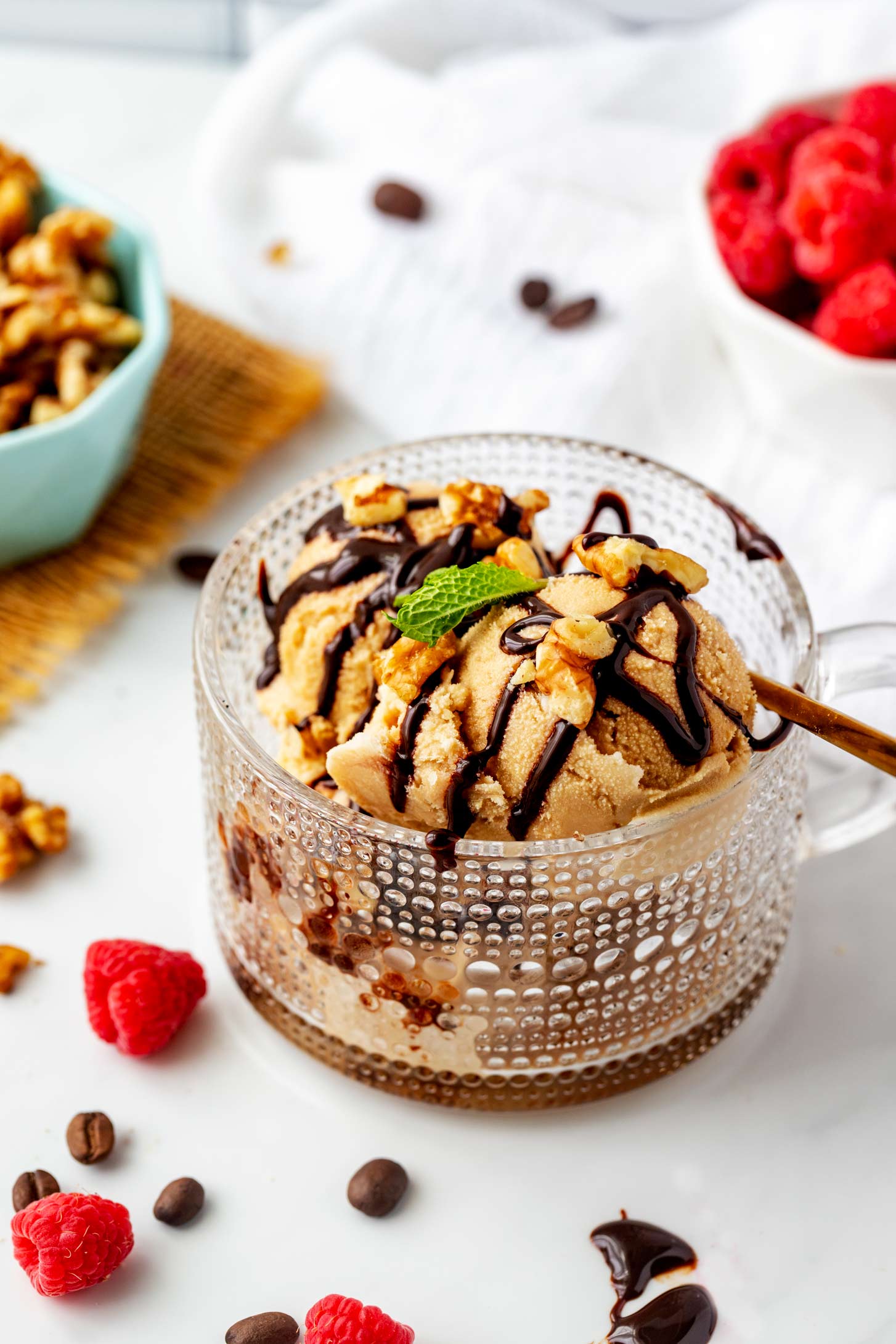 A glass coffee mug with Ninja Creami coffee ice cream in it drizzled with chocolate sauce and topped with walnuts.