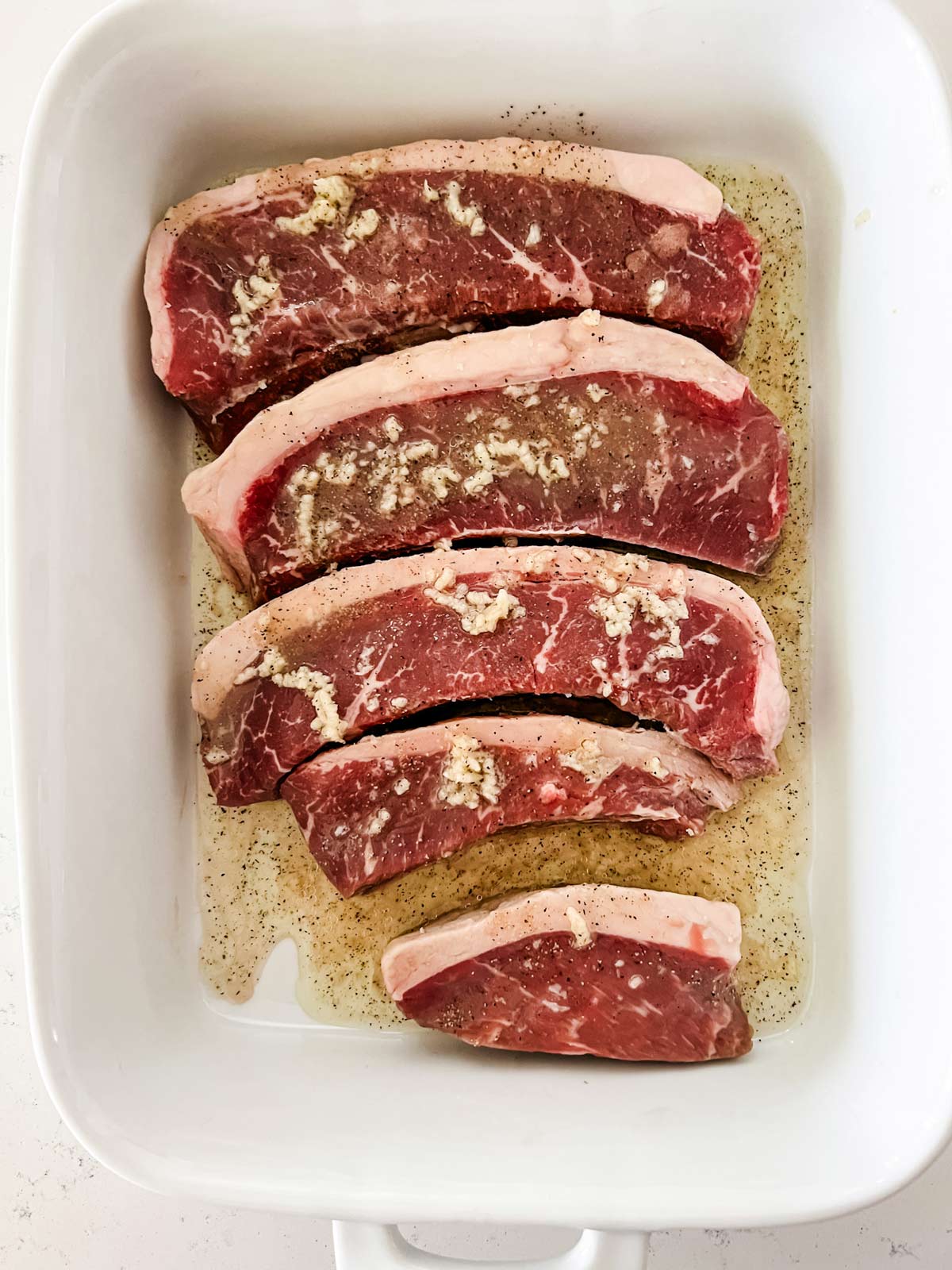 Picanha steaks marinating in a shallow dish.