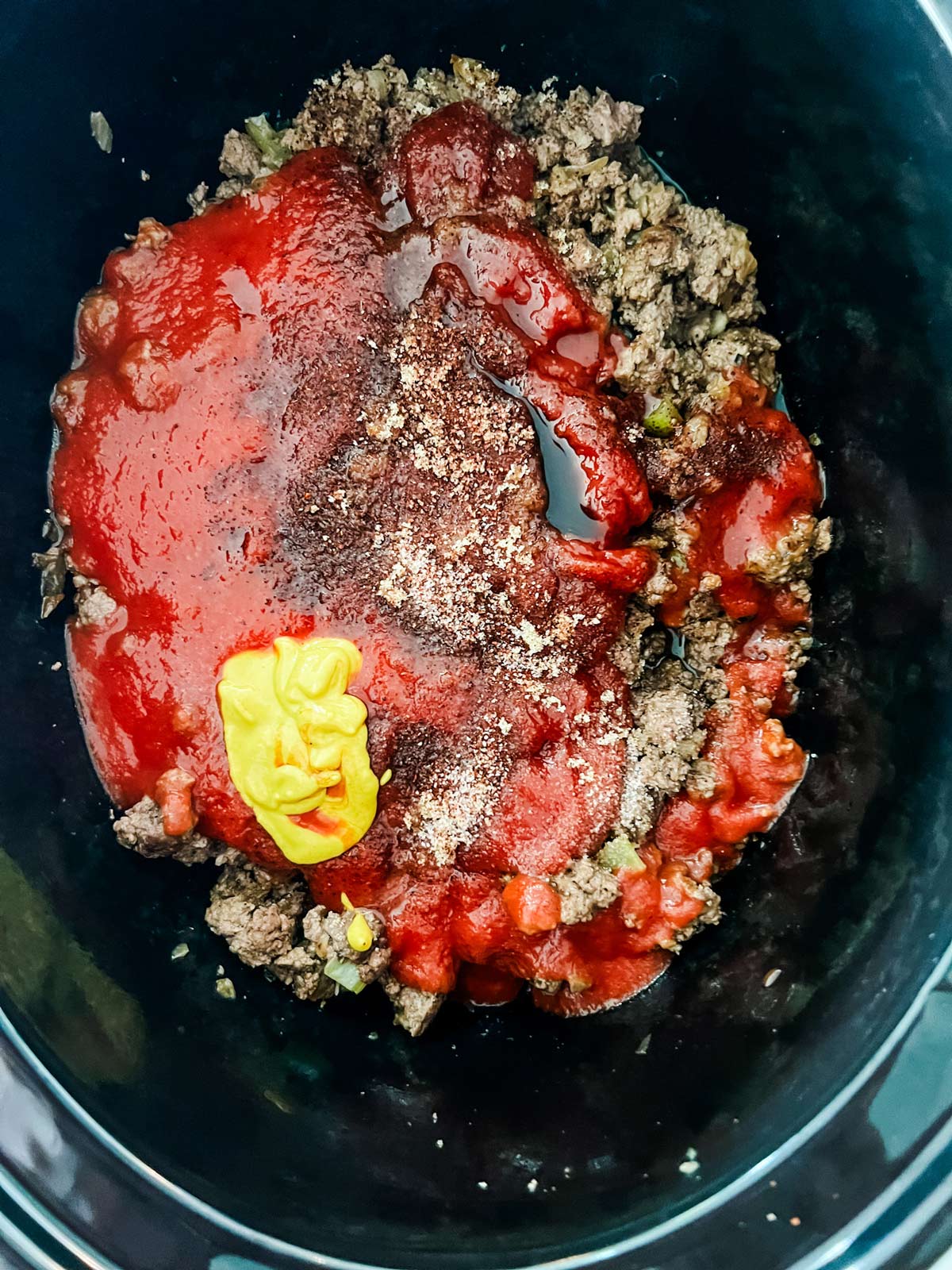 Ketchup, tomato sauce, Worcestershire, vinegar, mustard, sugar, chili powder and salt on top of ground beef, onion, and celery in a slow cooker.