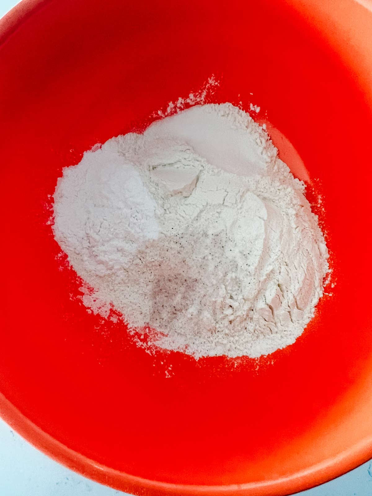 Flour and baking soda in a large orange bowl.