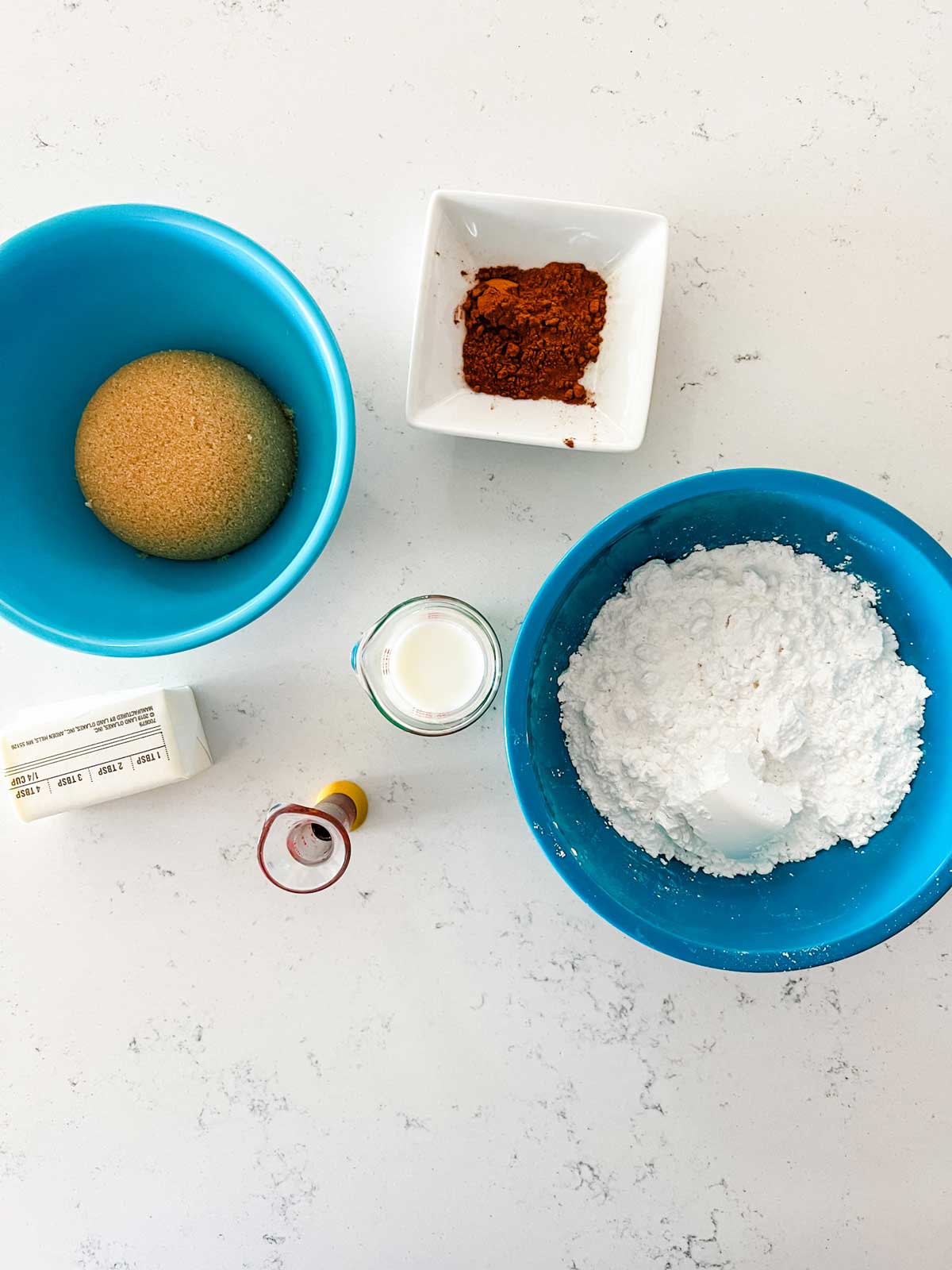 Overhead photo of brown sugar, cinnamon, powdered sugar, milk, vanilla, and butter.