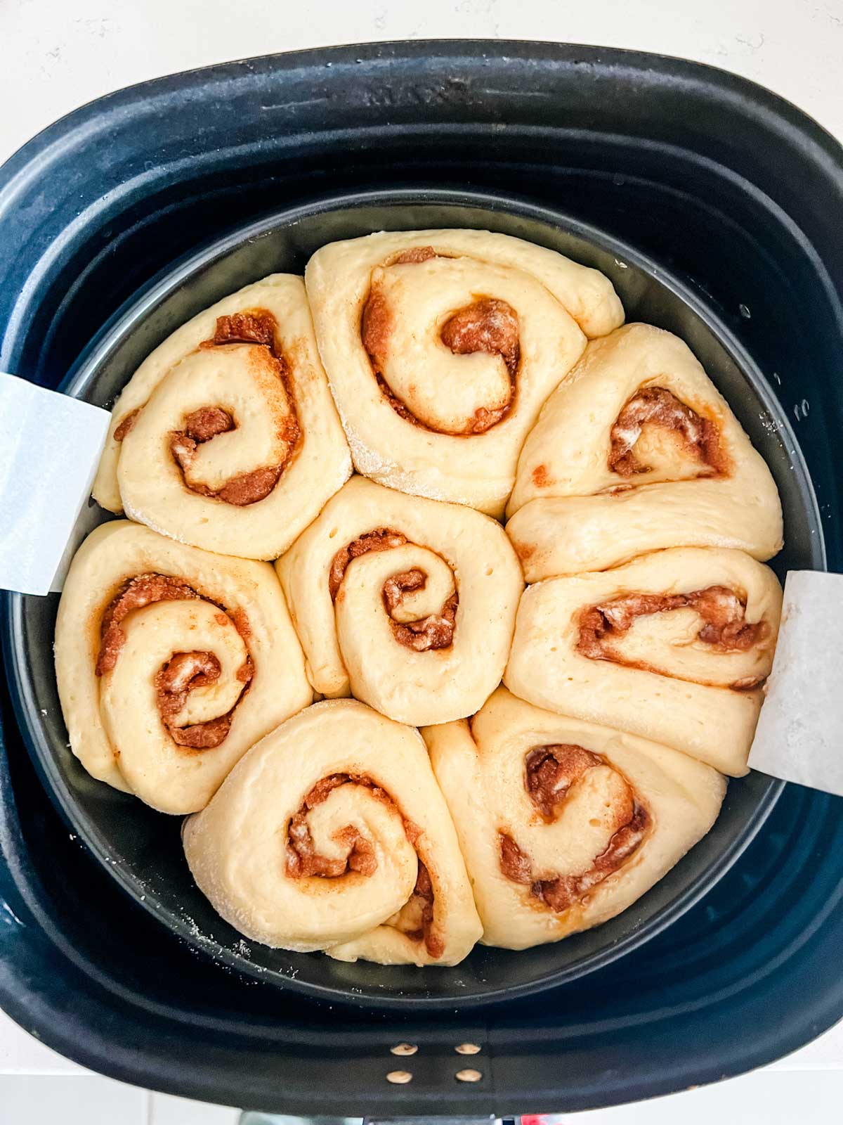 Cinnamon rolls in an air fryer basket ready to cook.