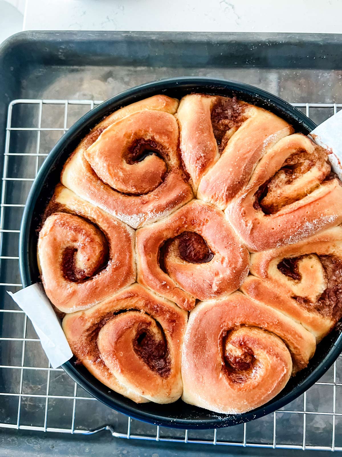 Overhead photo of cinnamon rolls in a cake pan fresh from the air fryer.