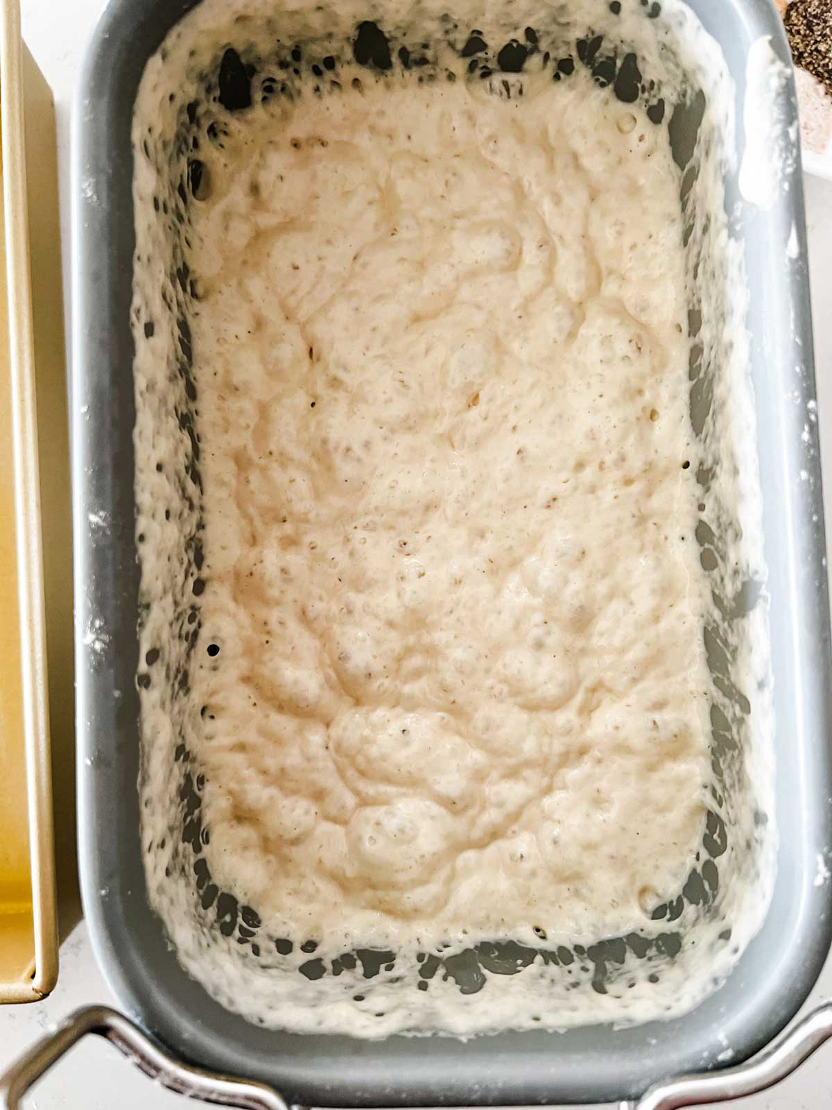 Focaccia bread dough in a bread machine pan.