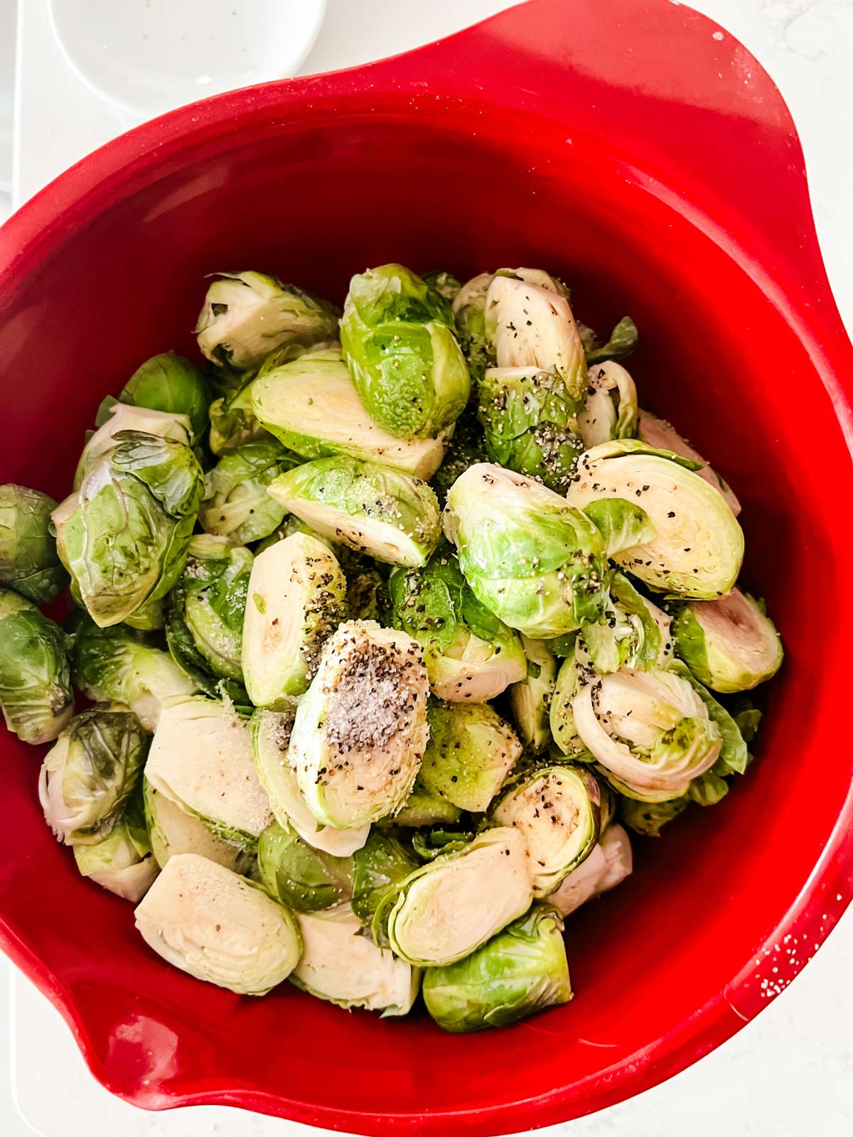 Seasoned brussels sprouts in a red bowl.